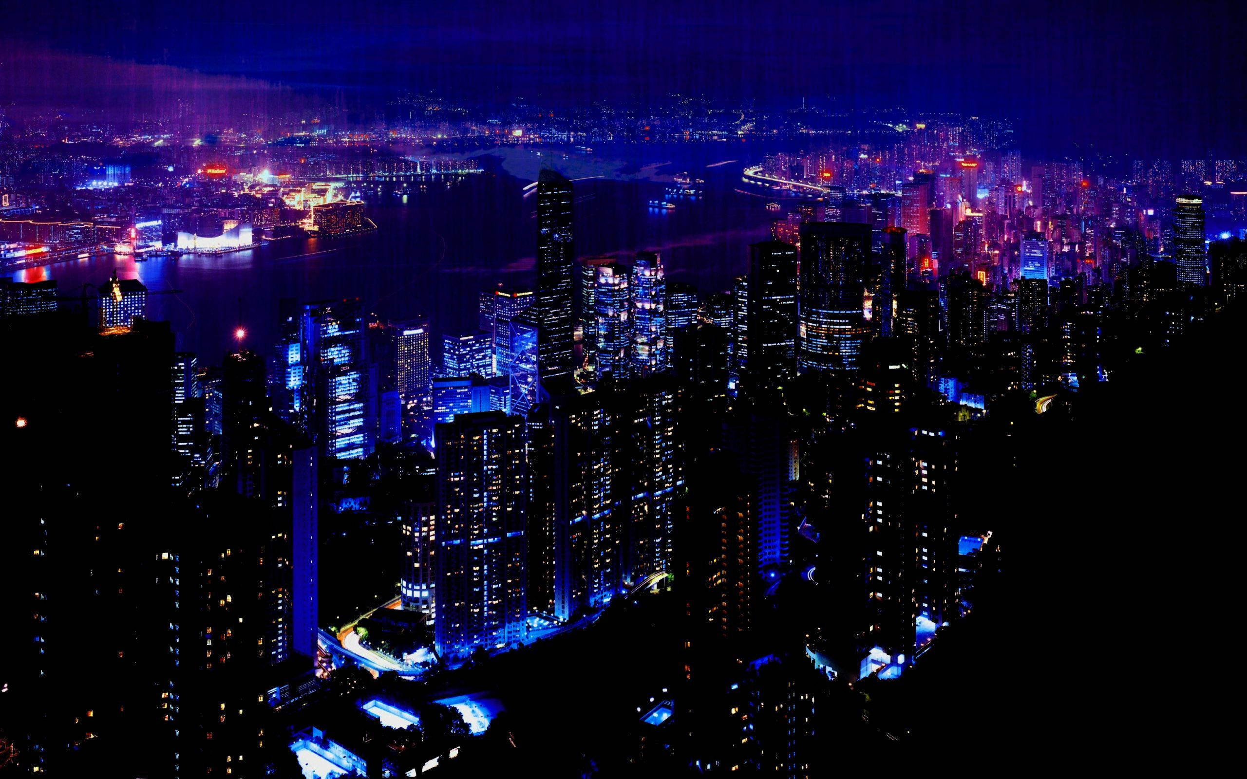 桌布 壁紙 — 夜間廣闊城市景觀的鳥瞰圖，藍色和紅色的發光燈光在水面上反射。