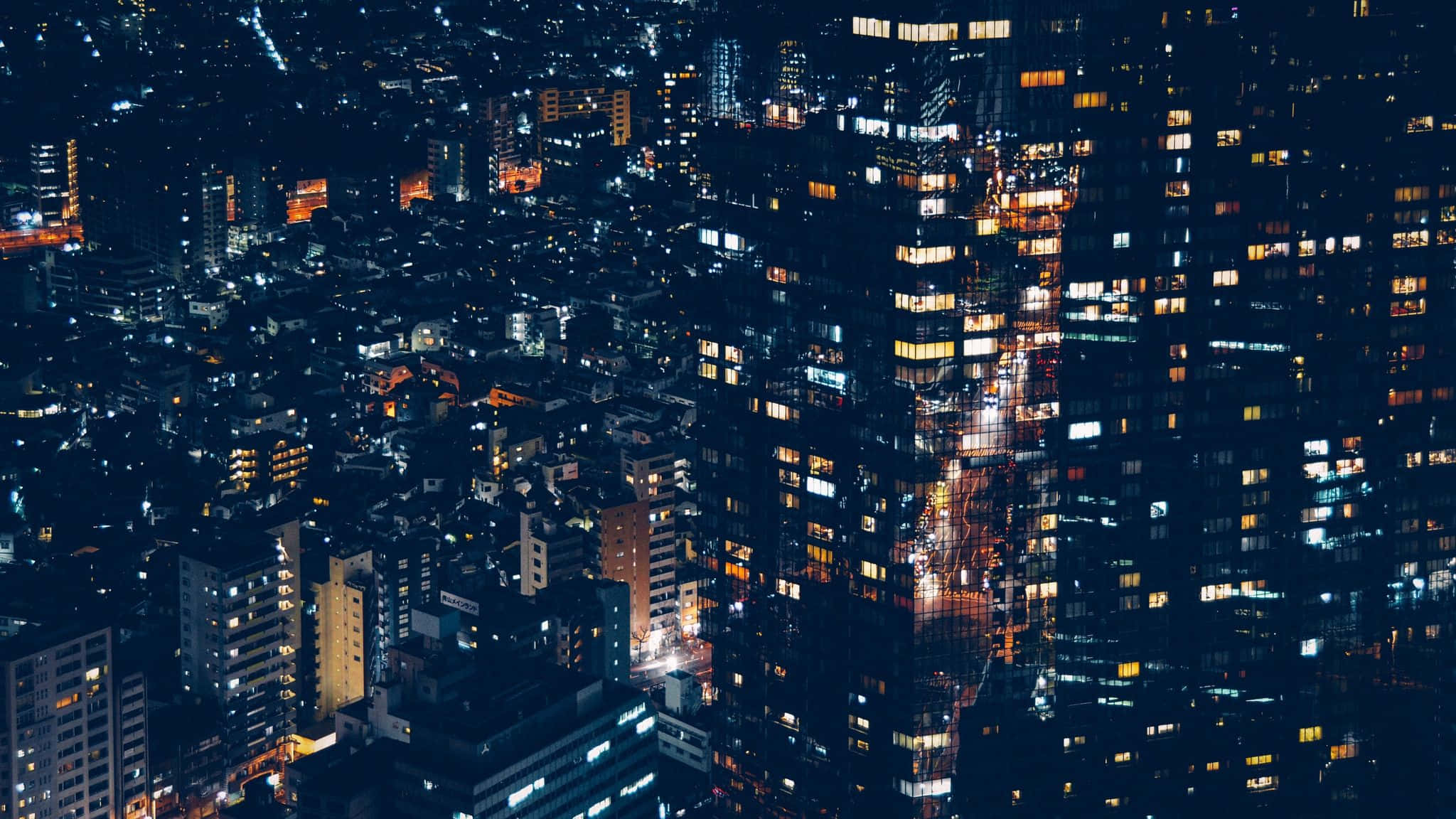 2048x1152 Aesthetic 桌布 壁紙 — 夜間廣闊城市的鳥瞰圖，發光的窗戶和明亮的街道營造出充滿活力的城市掛毯。