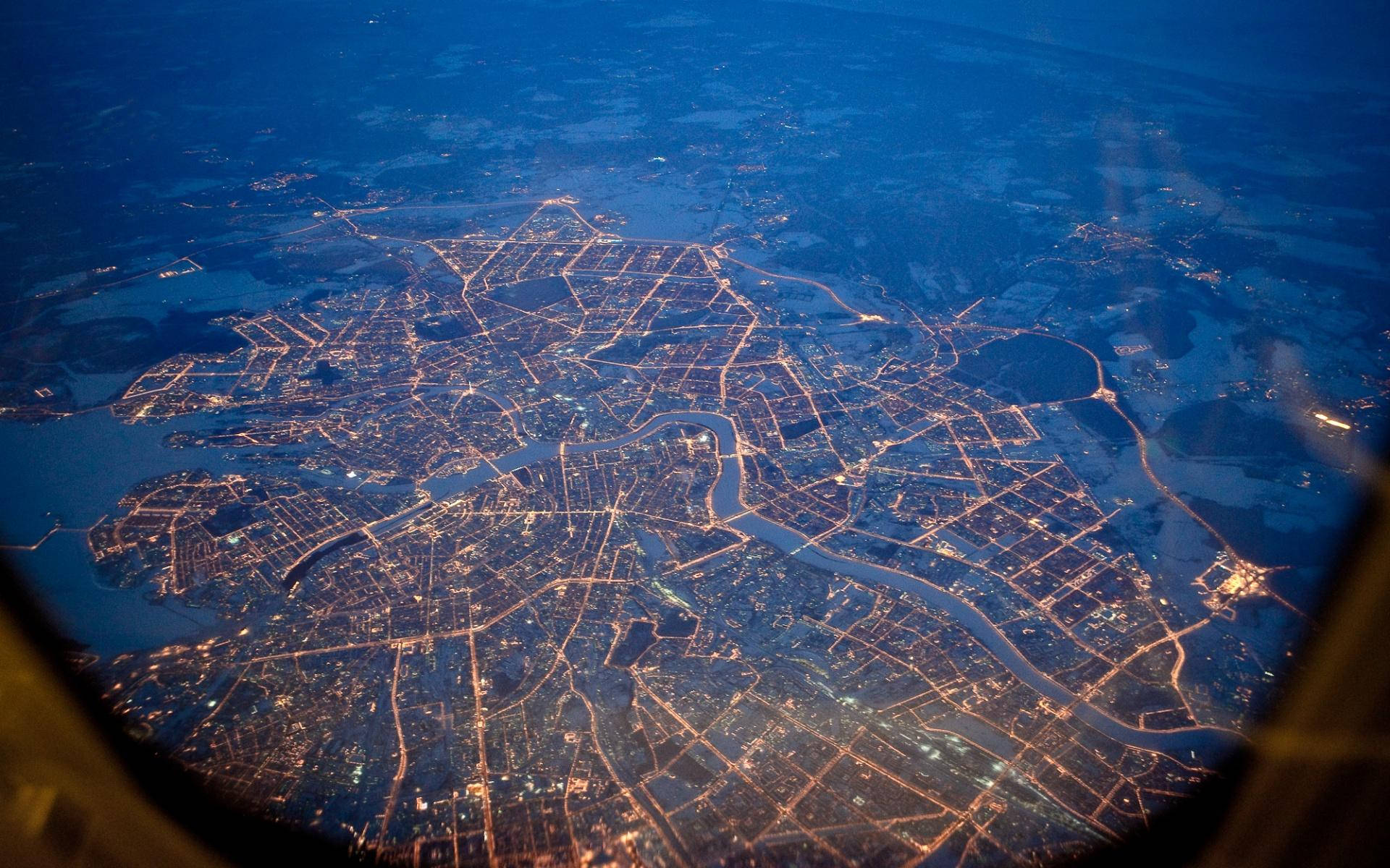 Saint Petersburg 桌布 壁紙 — 夜間廣闊城市的鳥瞰圖，發光的街道和河流蜿蜒穿過燈火通明的社區。