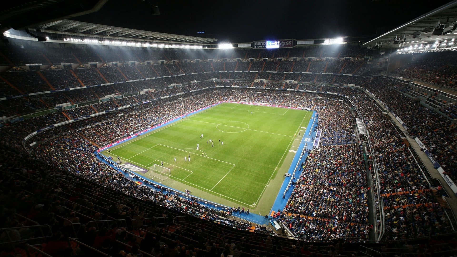 Soccer 4K 桌布 壁紙 — 夜間明亮燈光的足球場鳥瞰圖，充滿歡呼的球迷圍繞著充滿活力的綠色球場。
