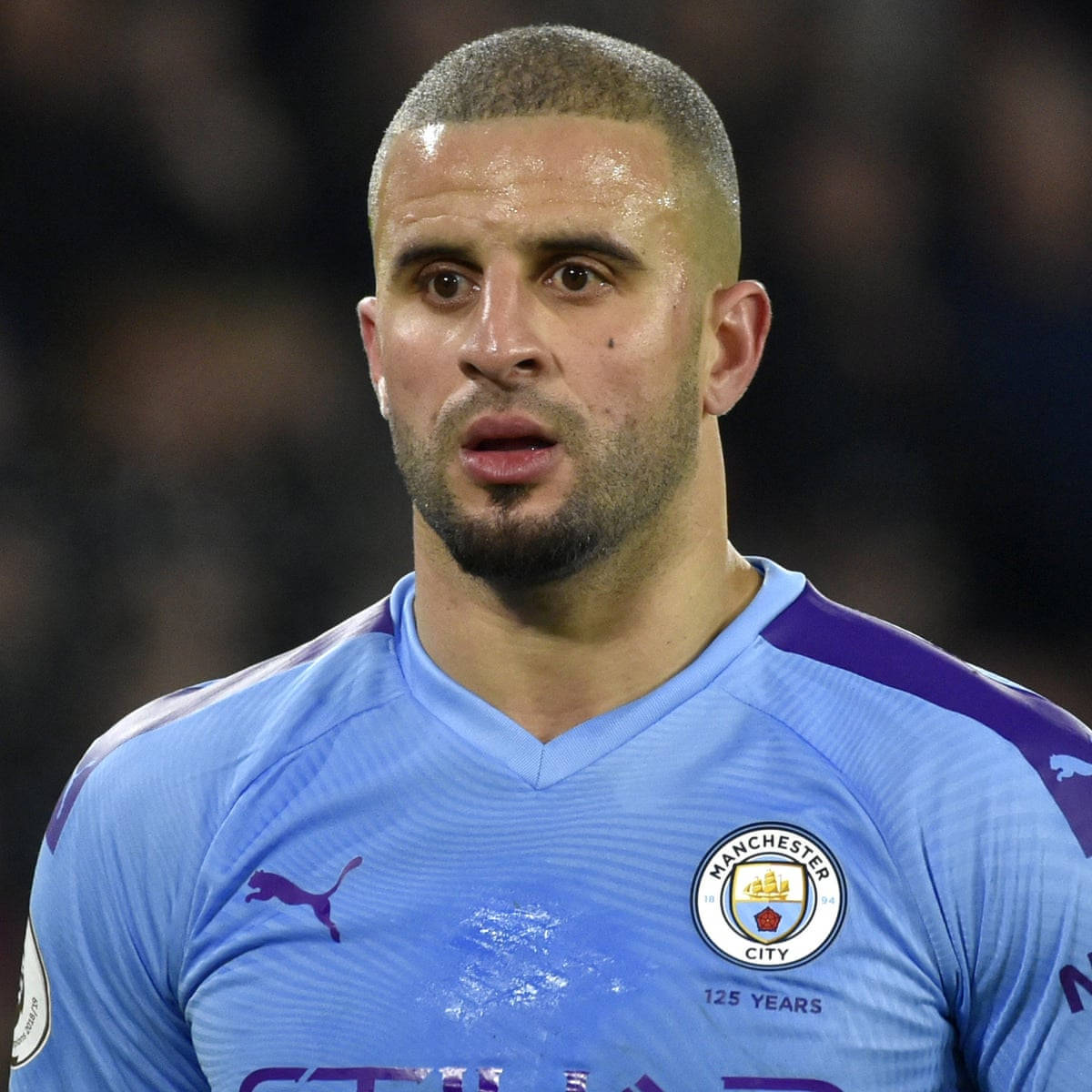 Kyle Walker 桌布 壁紙 — 夜間比賽中，身穿淺藍色曼城球衣（帶紫色點綴）的專注足球員特寫。