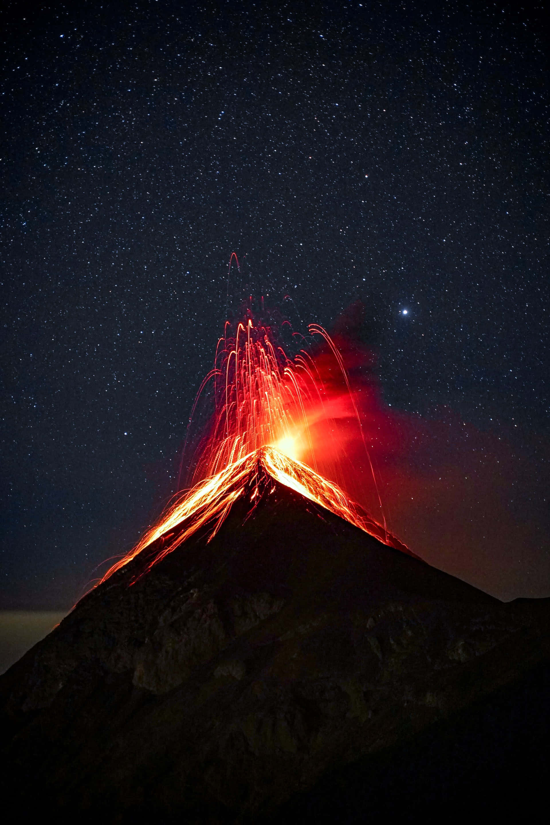 Earth Science 桌布 壁紙 — 夜間火山爆發，山頂上方有發光的熔岩流和星空。