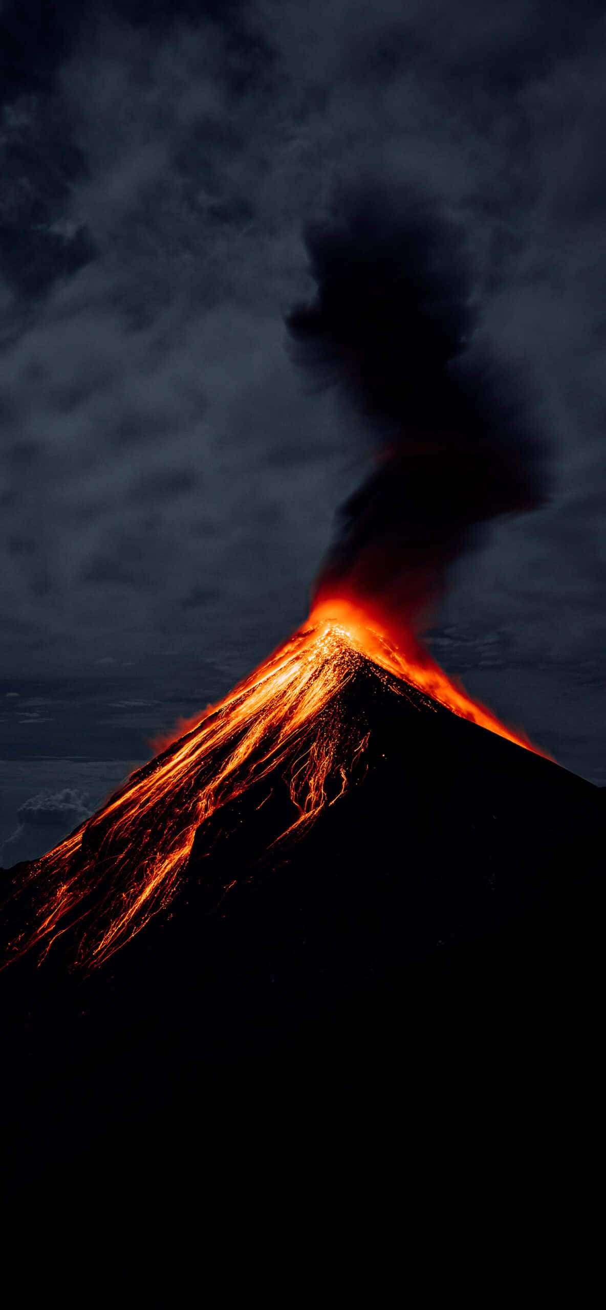 自然 桌布 壁紙 — 夜間火山爆發，熾熱熔岩沿著黑暗山坡流下，濃煙升入暴風雨的天空。