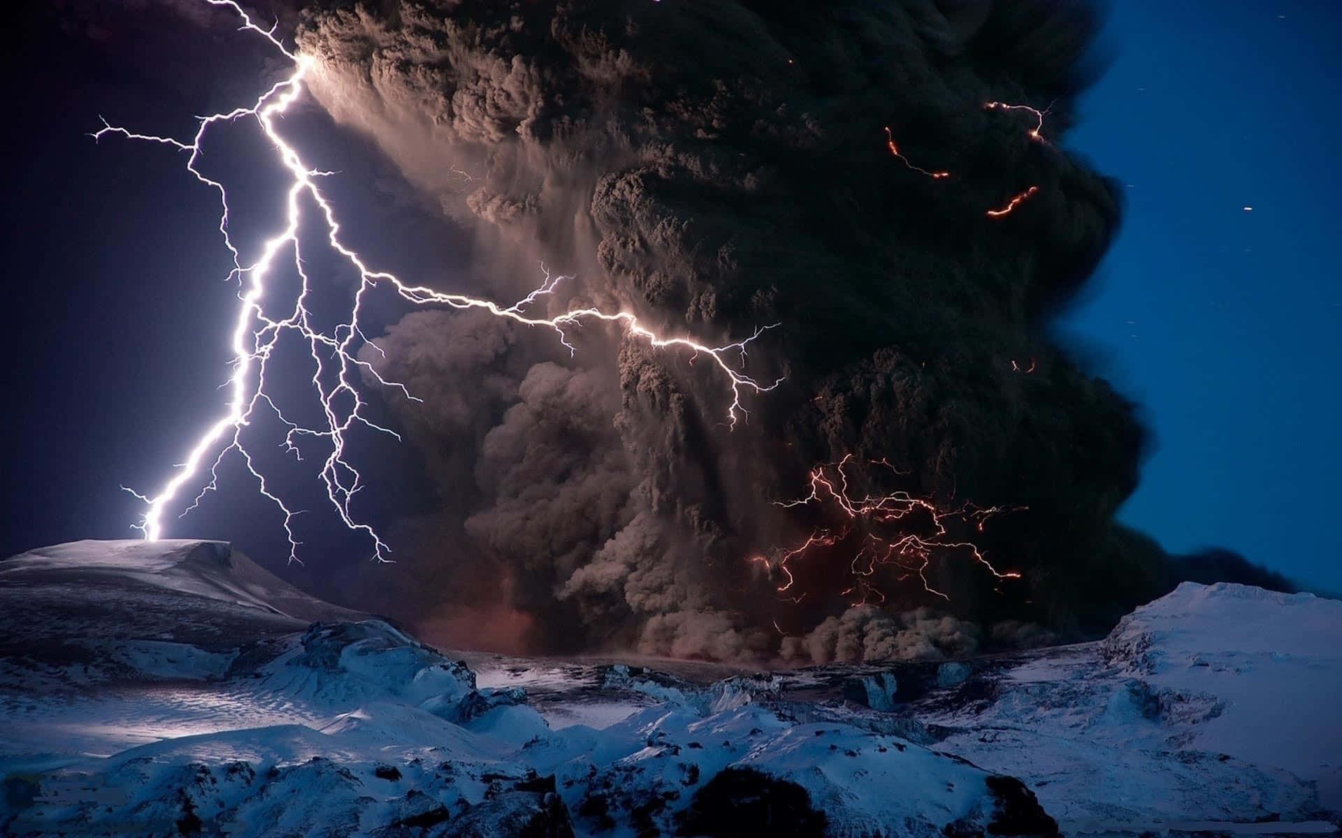 龍捲風 桌布 壁紙 — 夜間火山爆發，閃電穿過巨大的火山灰雲，下方是積雪覆蓋的地形。