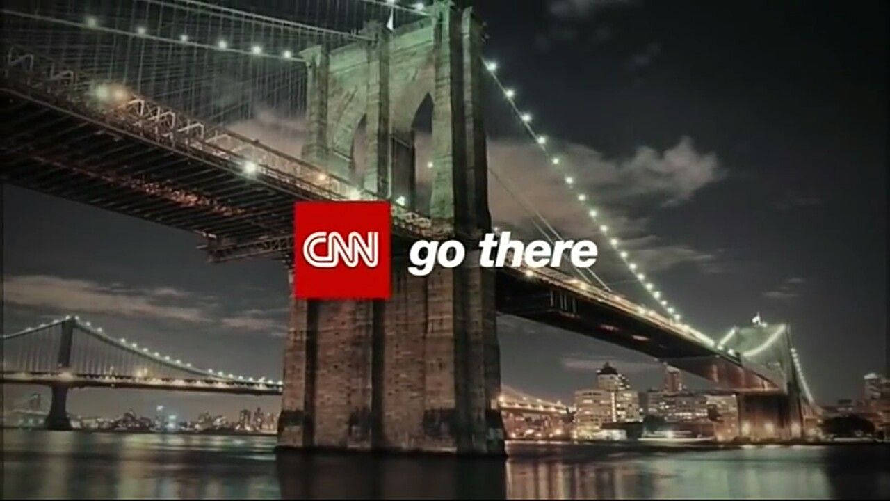 Cnn 桌布 壁紙 — 夜間照亮的布魯克林大橋，城市燈光倒映在水面上，並疊加CNN go there標誌。