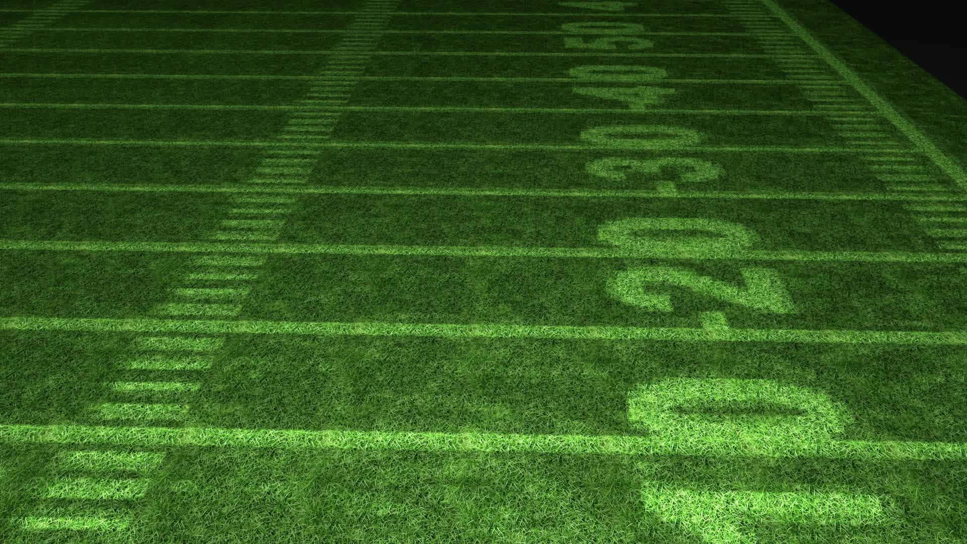 Football Field 桌布 壁紙 — 夜間球場燈光下，充滿活力的綠色足球場的低角度視圖，帶有清晰的白線和數字。