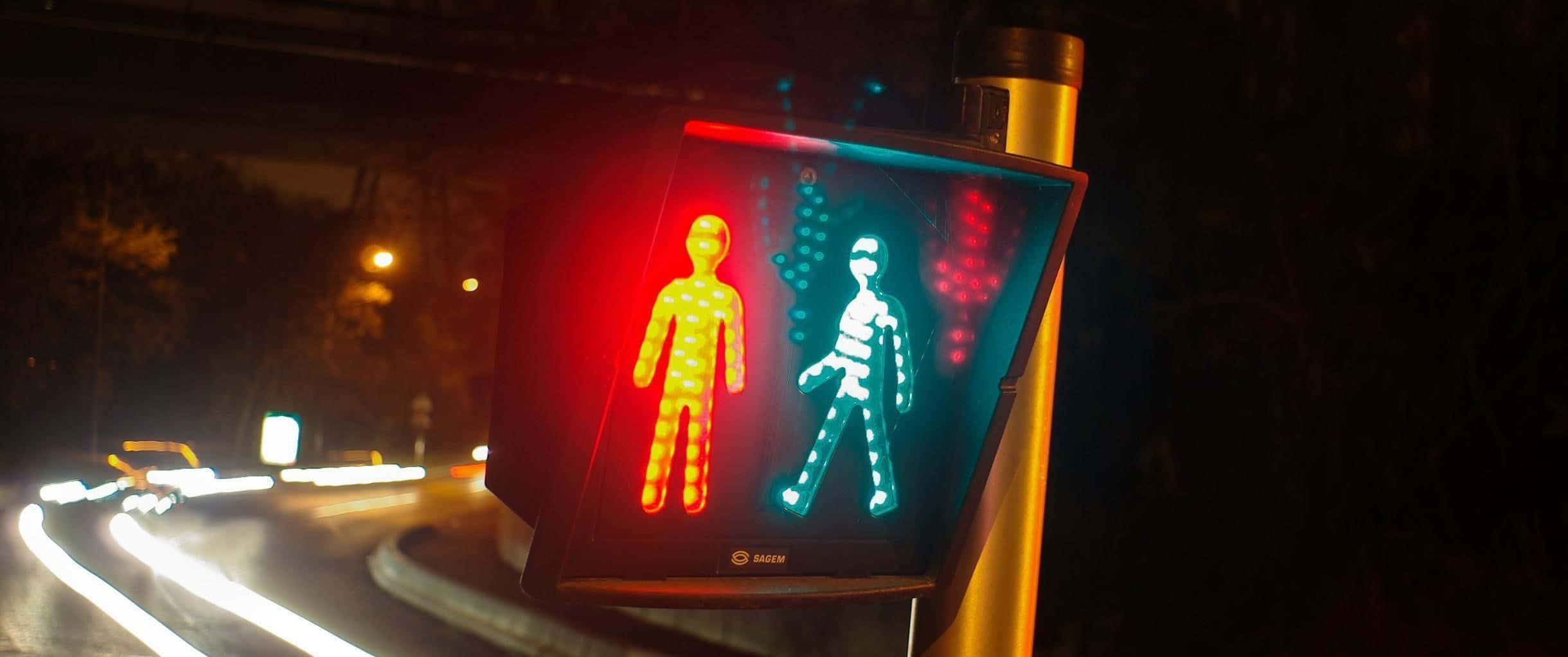 Stop Light 桌布 壁紙 — 夜間發光的行人穿越道號誌，在模糊的城市街燈背景下顯示紅色和綠色的人物。