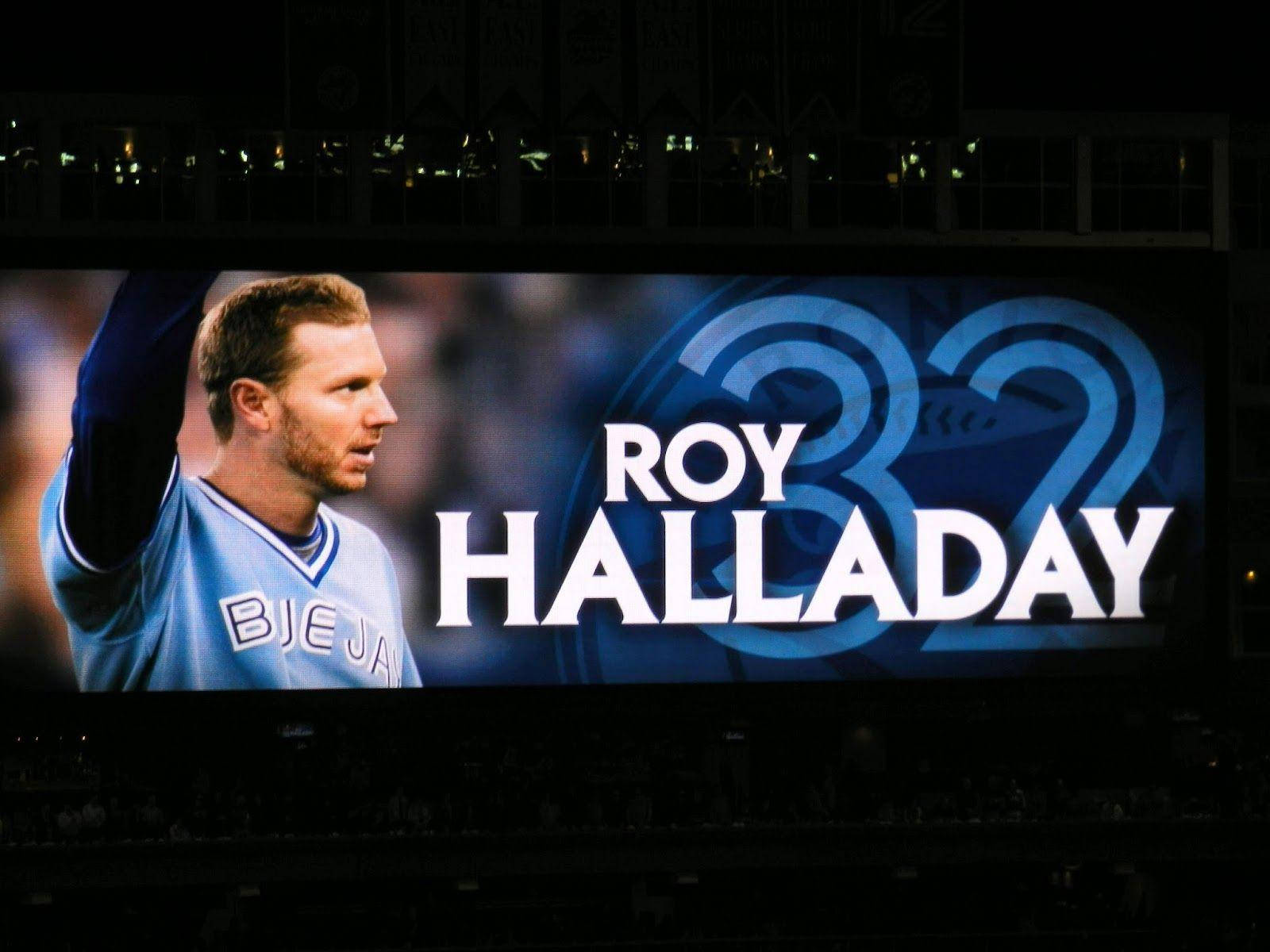 roy halladay 桌布 壁紙 — 夜間的大型體育館螢幕顯示對Roy Halladay的致敬，藍色背景上以粗體白色文字顯示他的名字和32號。