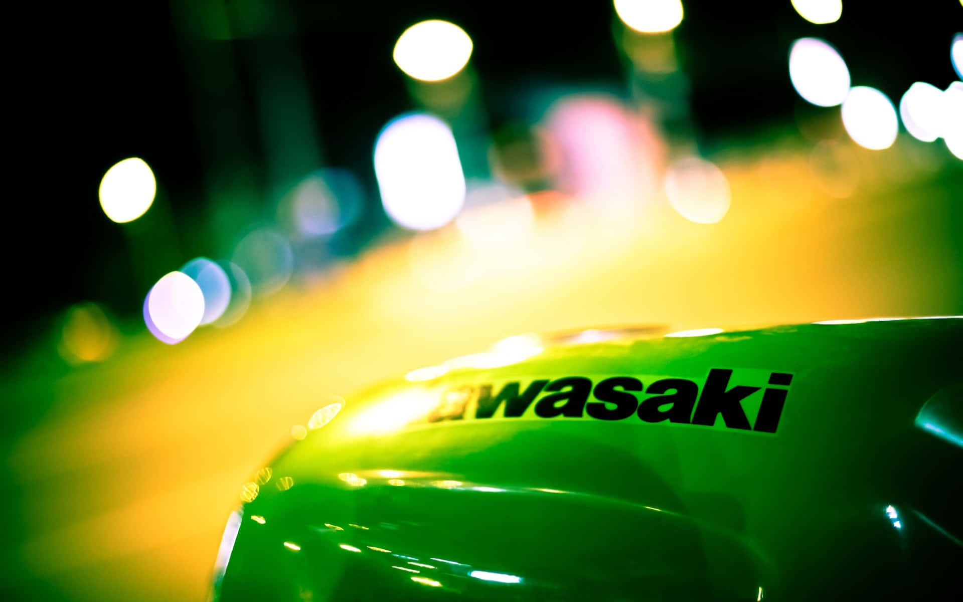 Kawasaki Desktop 桌布 壁紙 — 夜間霓虹燈下綠色川崎機車油箱的特寫，帶有模糊的城市散景。