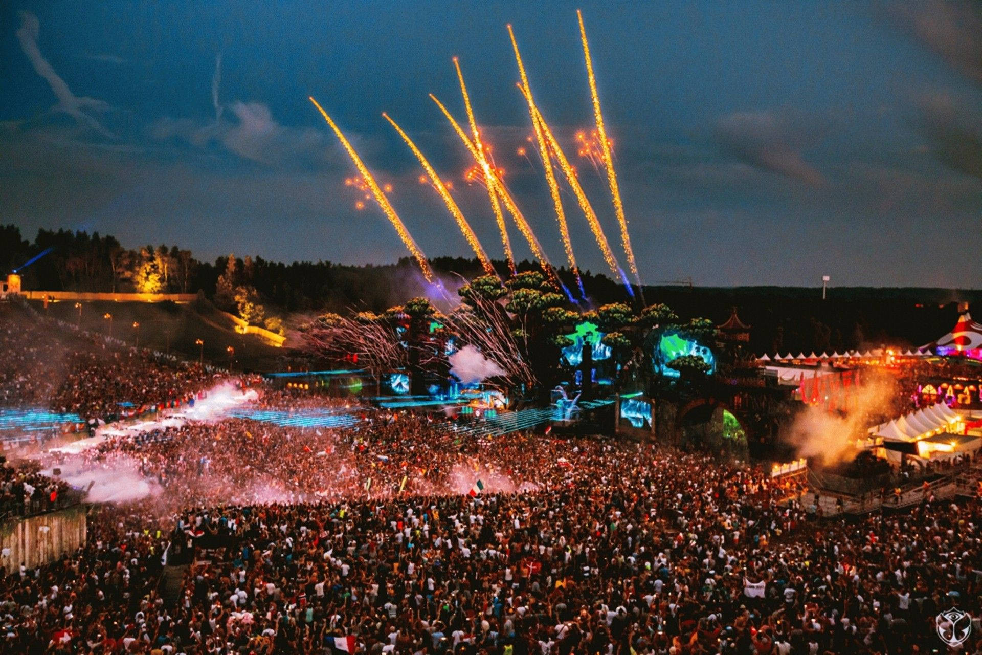 Tomorrowland 桌布 壁紙 — 夜間音樂節上，大量人群被耀眼的煙火和充滿活力的舞台燈光照亮。