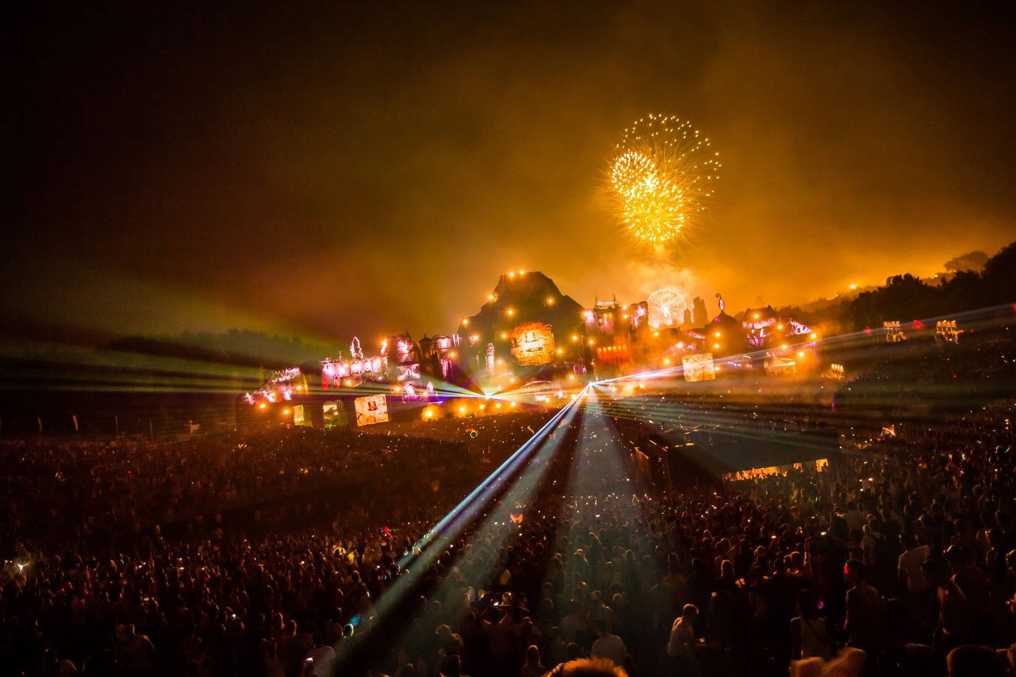 Tomorrowland 桌布 壁紙 — 夜間音樂節上，大量人群被舞台上耀眼的雷射燈光和金色煙火爆炸照亮。
