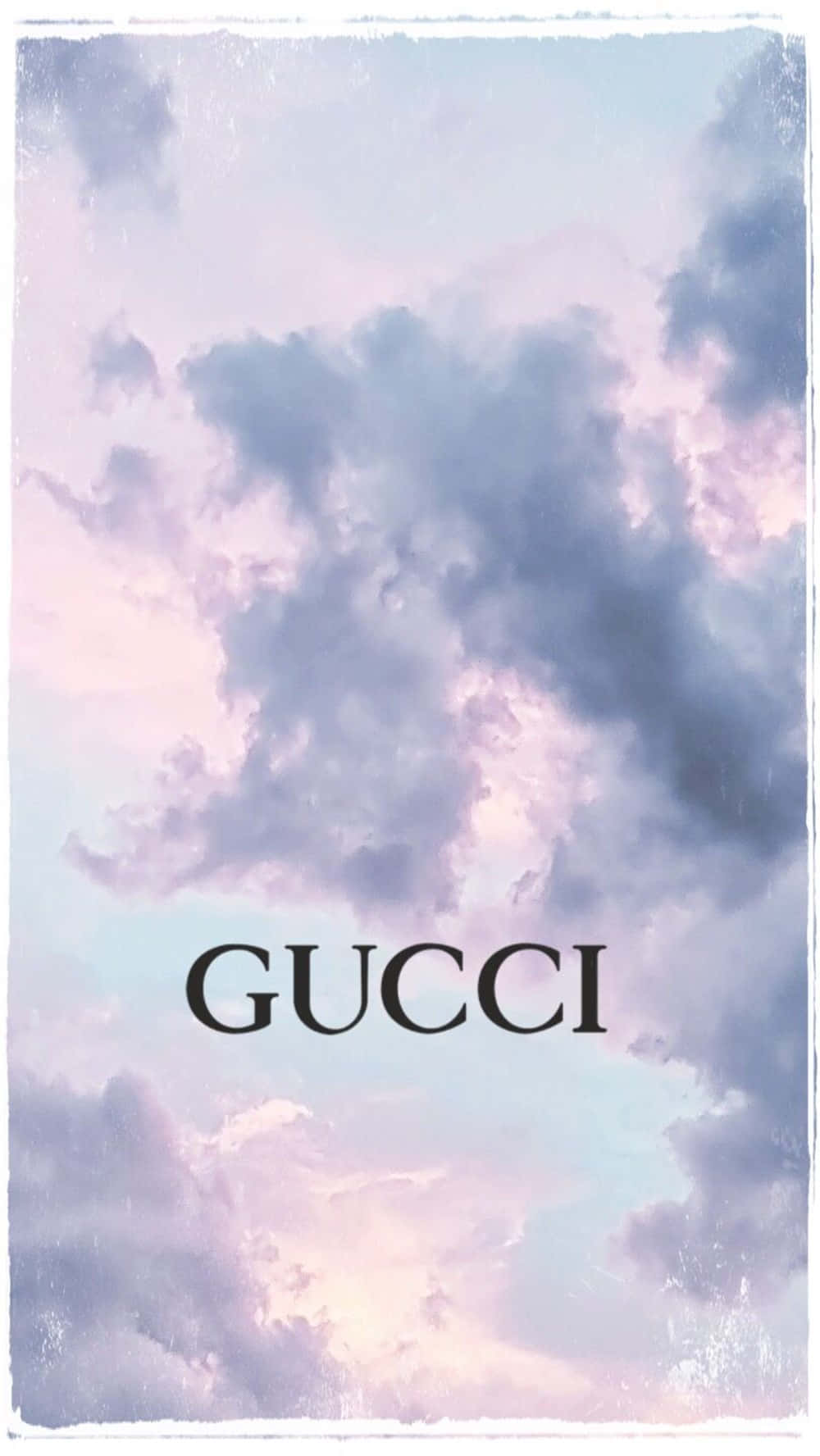 Purple Gucci 桌布 壁紙 — 夢幻的粉彩天空，有柔和的薰衣草色和藍色雲朵，中間是粗體黑色Gucci標誌，放在復古紋理框架中。