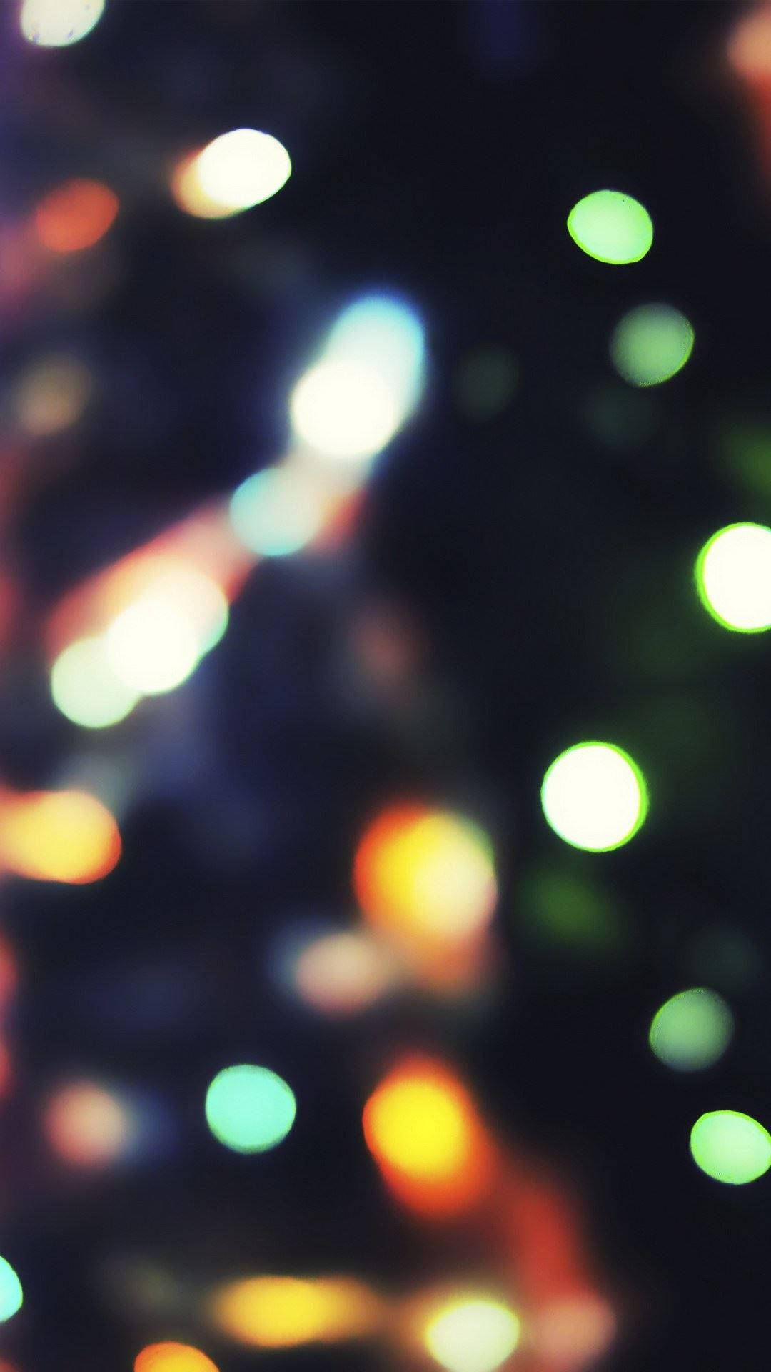 Christmas Lights iPhone 桌布 壁紙 — 夢幻般的散景效果，在黑暗背景上呈現綠色、橙色和白色光芒的發光球體。