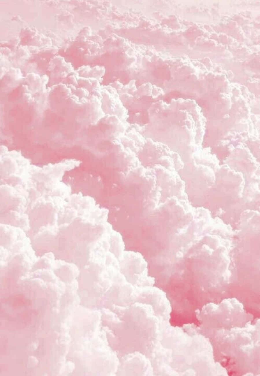 Pink And White Aesthetic 桌布 壁紙 — 夢幻般的空中視圖，柔軟的雲朵染上柔和的粉彩粉紅色調，映襯著溫柔的天空。