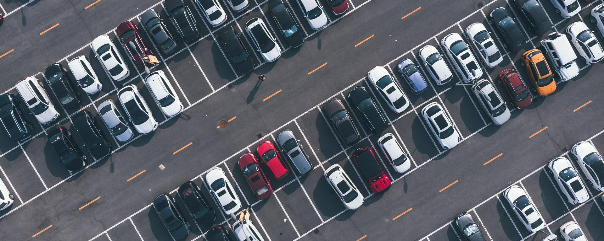 汽車 桌布 壁紙 — 大型停車場的鳥瞰圖，停車場內排滿了在明亮日光下停泊的車輛。