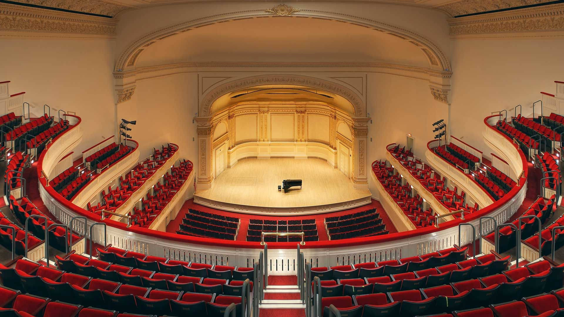 theatre 桌布 壁紙 — 大型劇院，紅色座椅，華麗建築，中央木質舞台上有一架孤獨的三角鋼琴。
