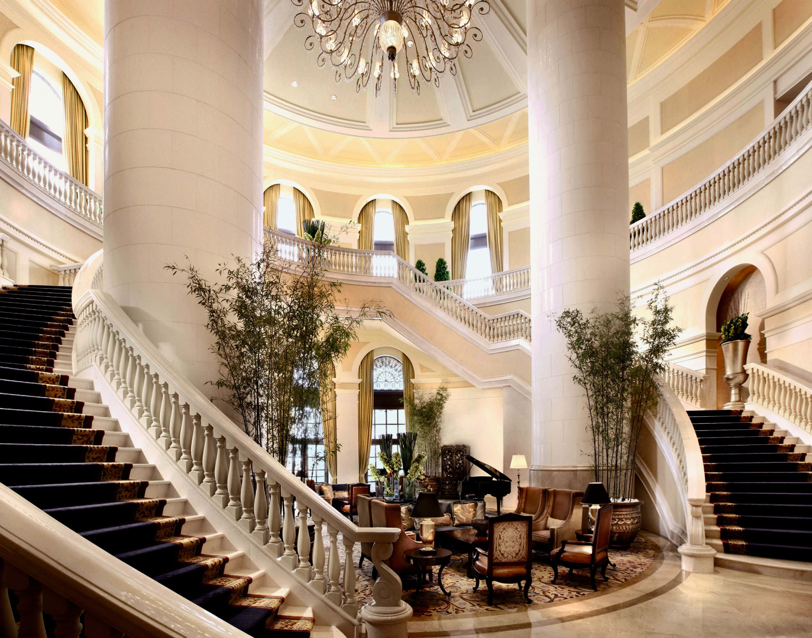Hotel 桌布 壁紙 — 大型圓形中庭，兩旁有高柱和優雅吊燈的宏偉大理石樓梯。