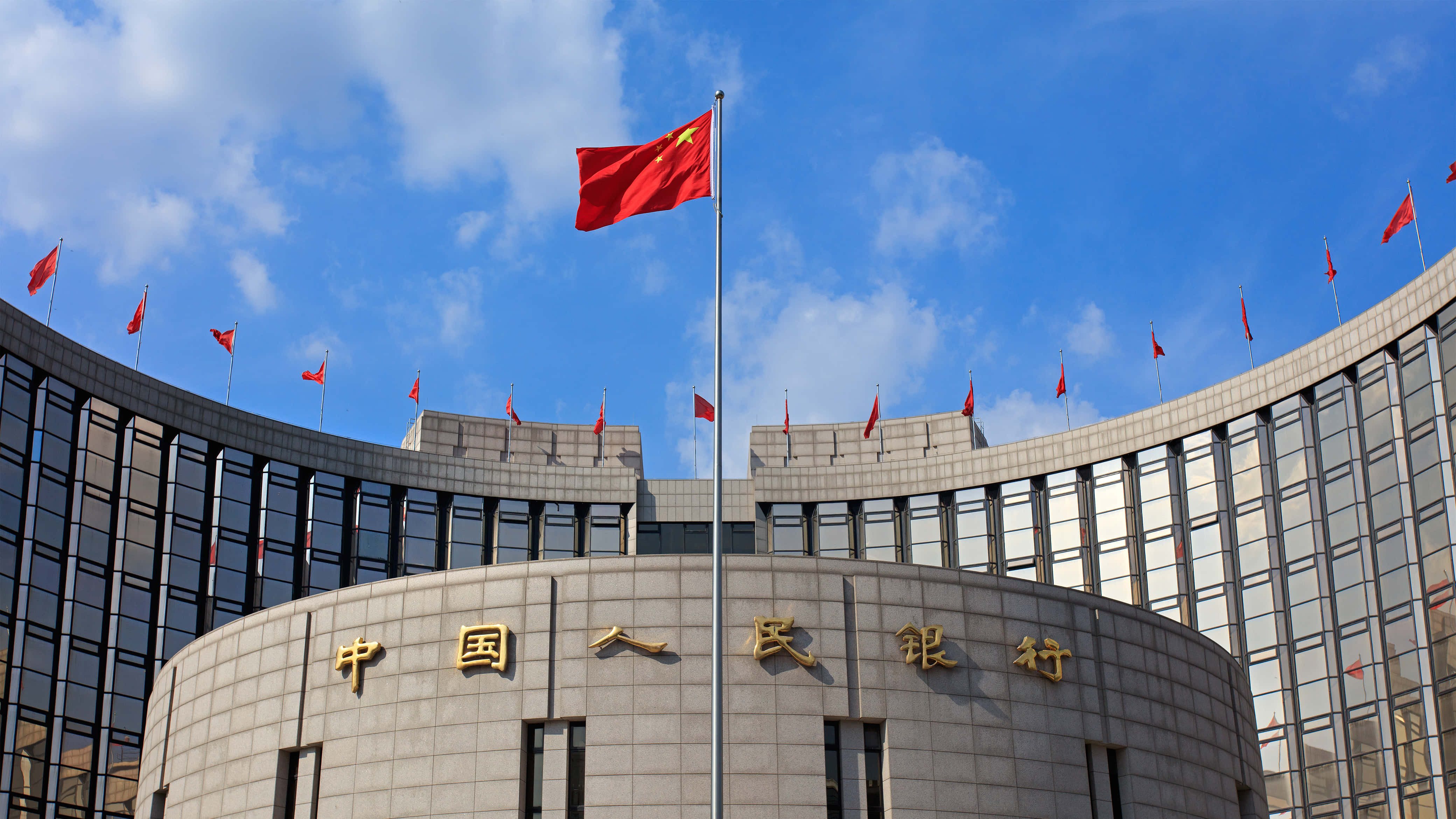 中國 桌布 壁紙 — 大型弧形建築，上有金色中文字和紅旗，在藍天白雲下飄揚。