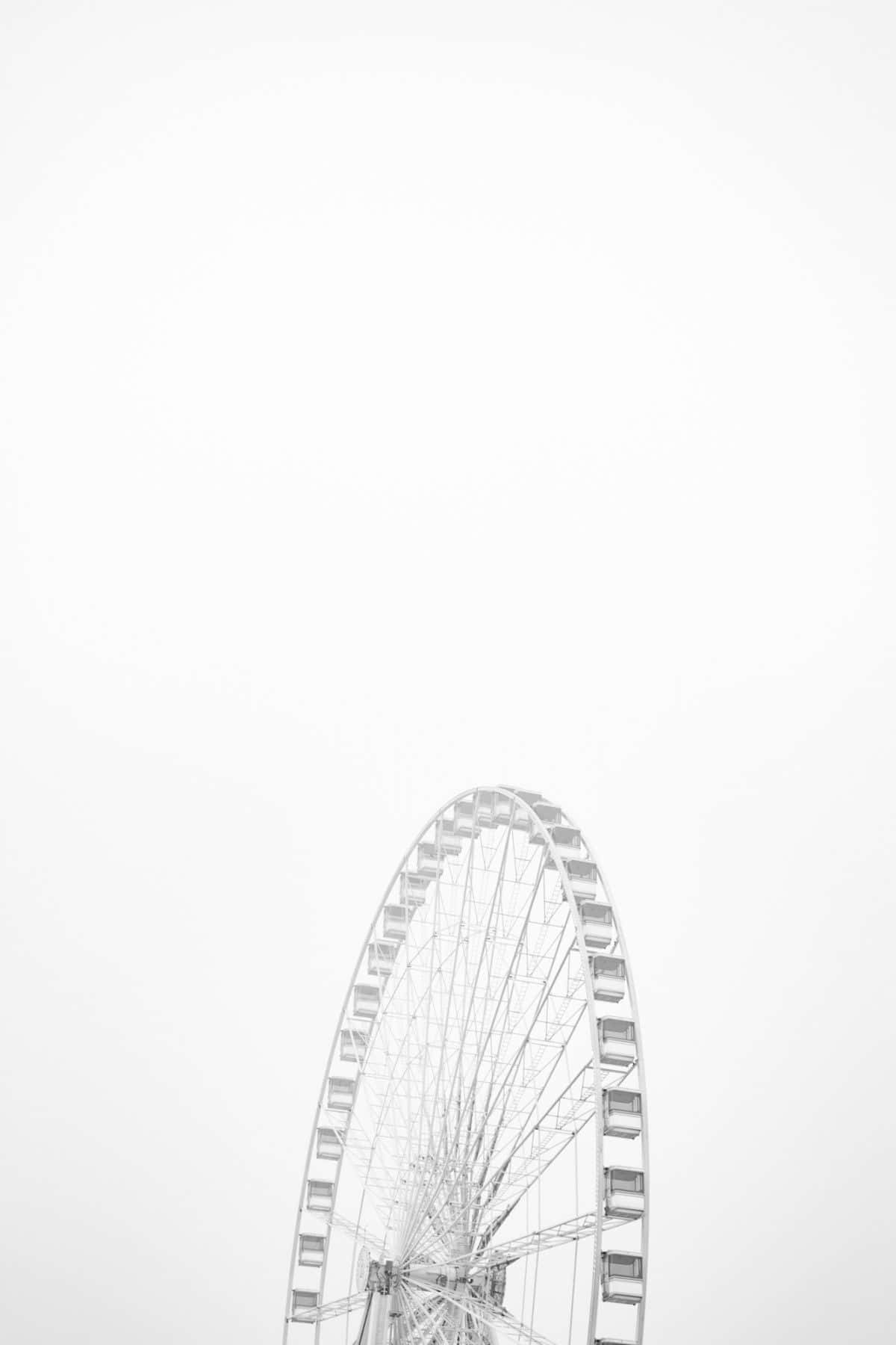 Soft White Aesthetic 桌布 壁紙 — 大型摩天輪在廣闊多雲的天空中升起的極簡黑白照片。