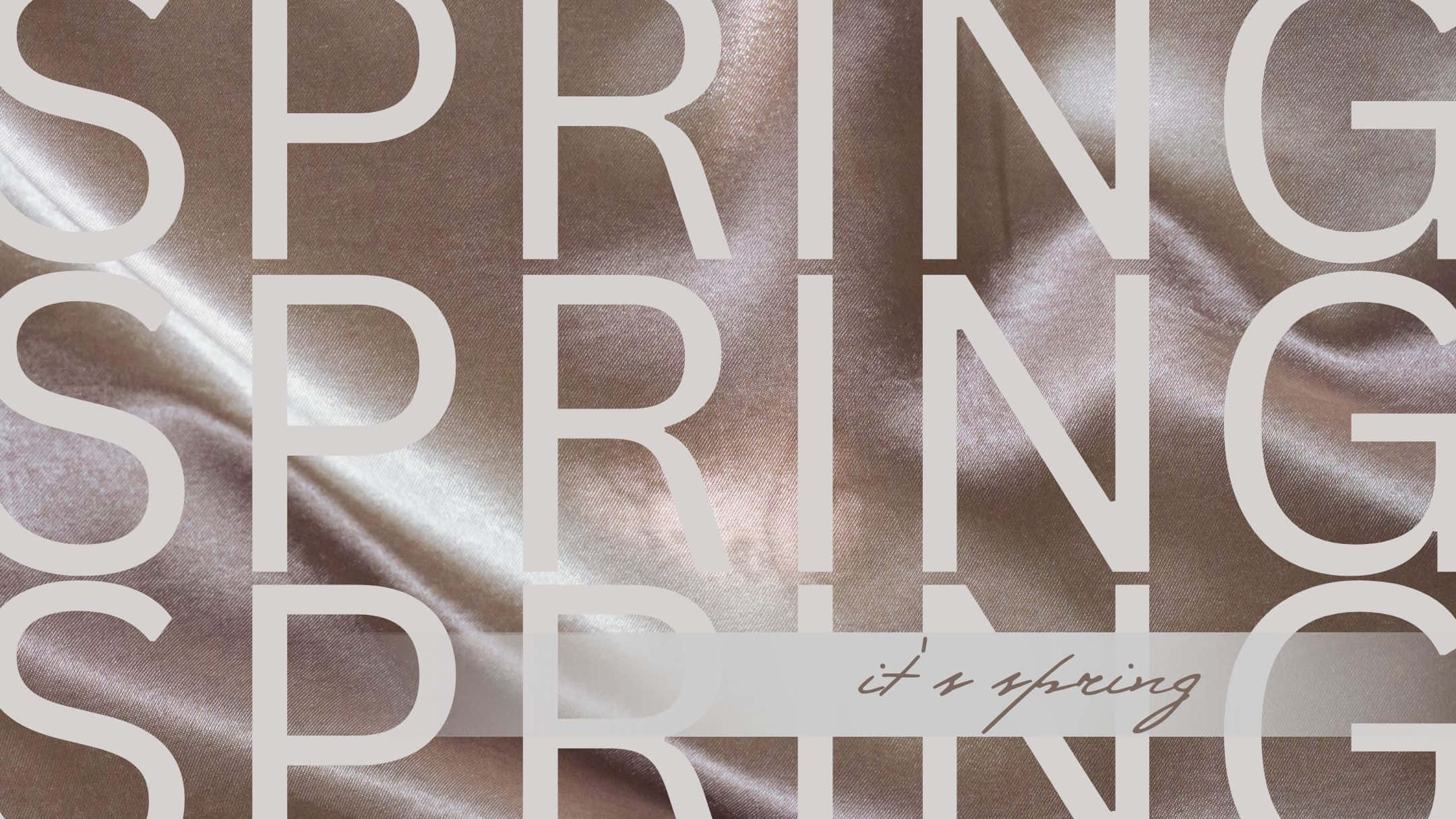 Spring Aesthetic 桌布 壁紙 — 大型白色「SPRING」字母在閃爍的玫瑰金緞面上重複出現，並附有草書「it's spring」標籤。