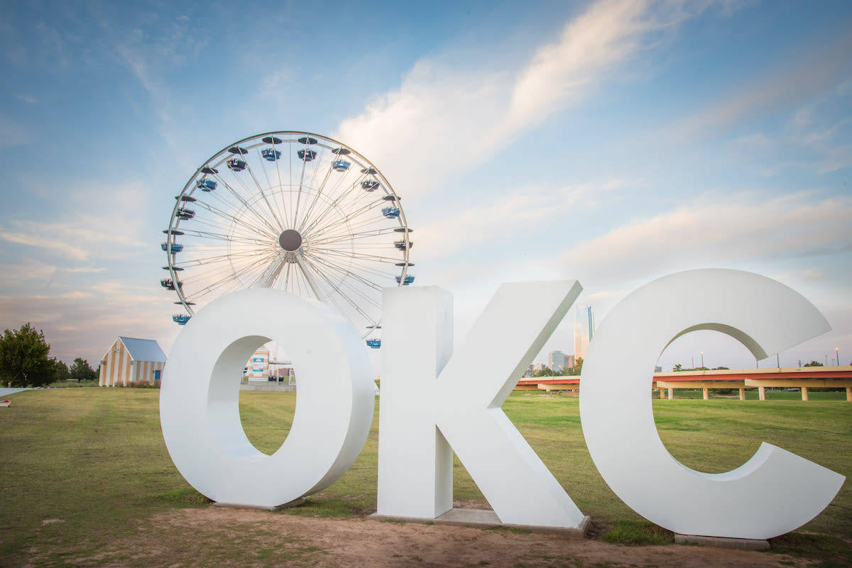 Oklahoma 桌布 壁紙 — 大型白色OKC字母矗立在草地上，背景有摩天輪和天空。