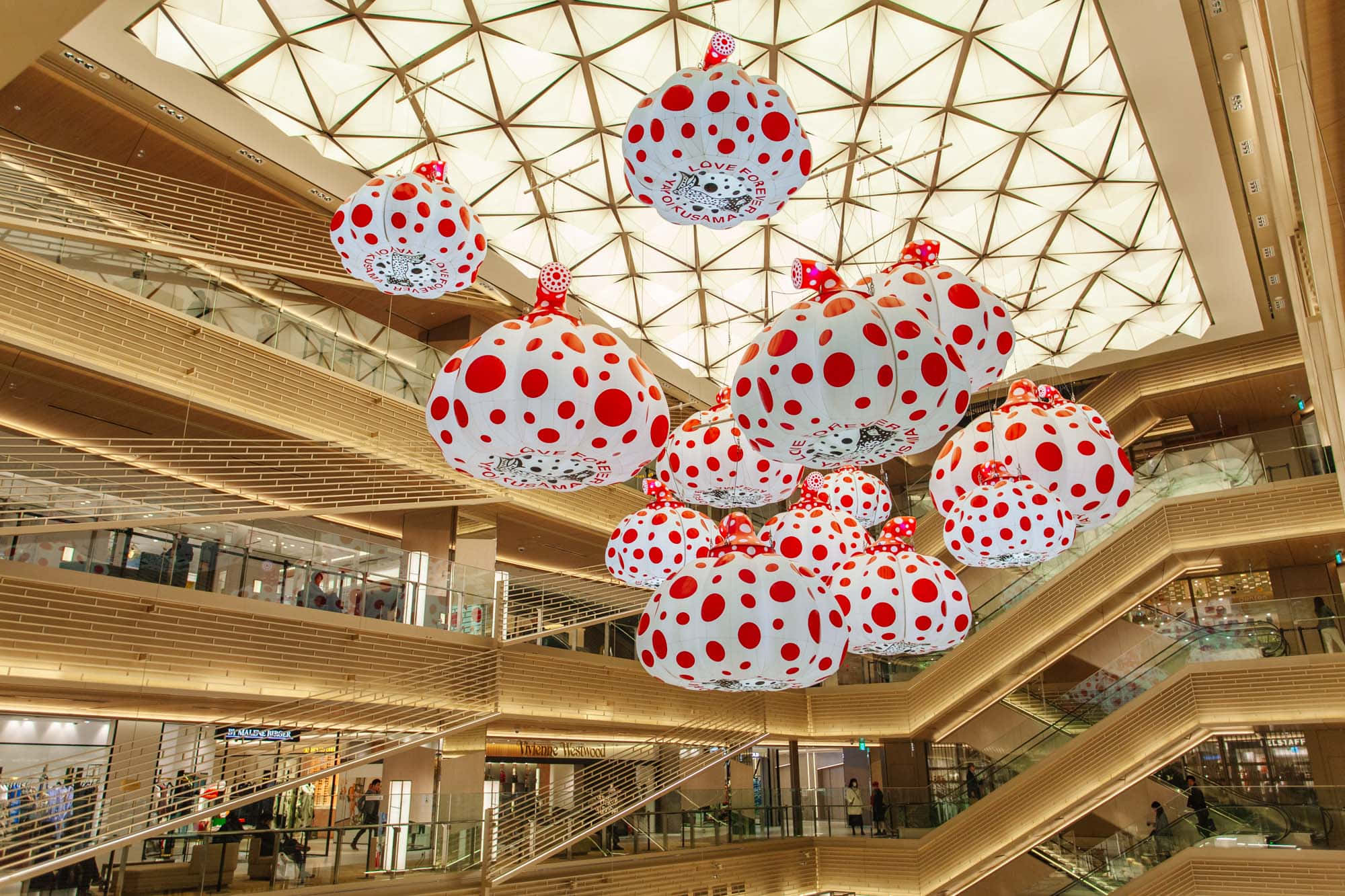 Mall 桌布 壁紙 — 大型白色圓點雕塑懸掛在幾何玻璃天花板上，位於多層購物中心內。