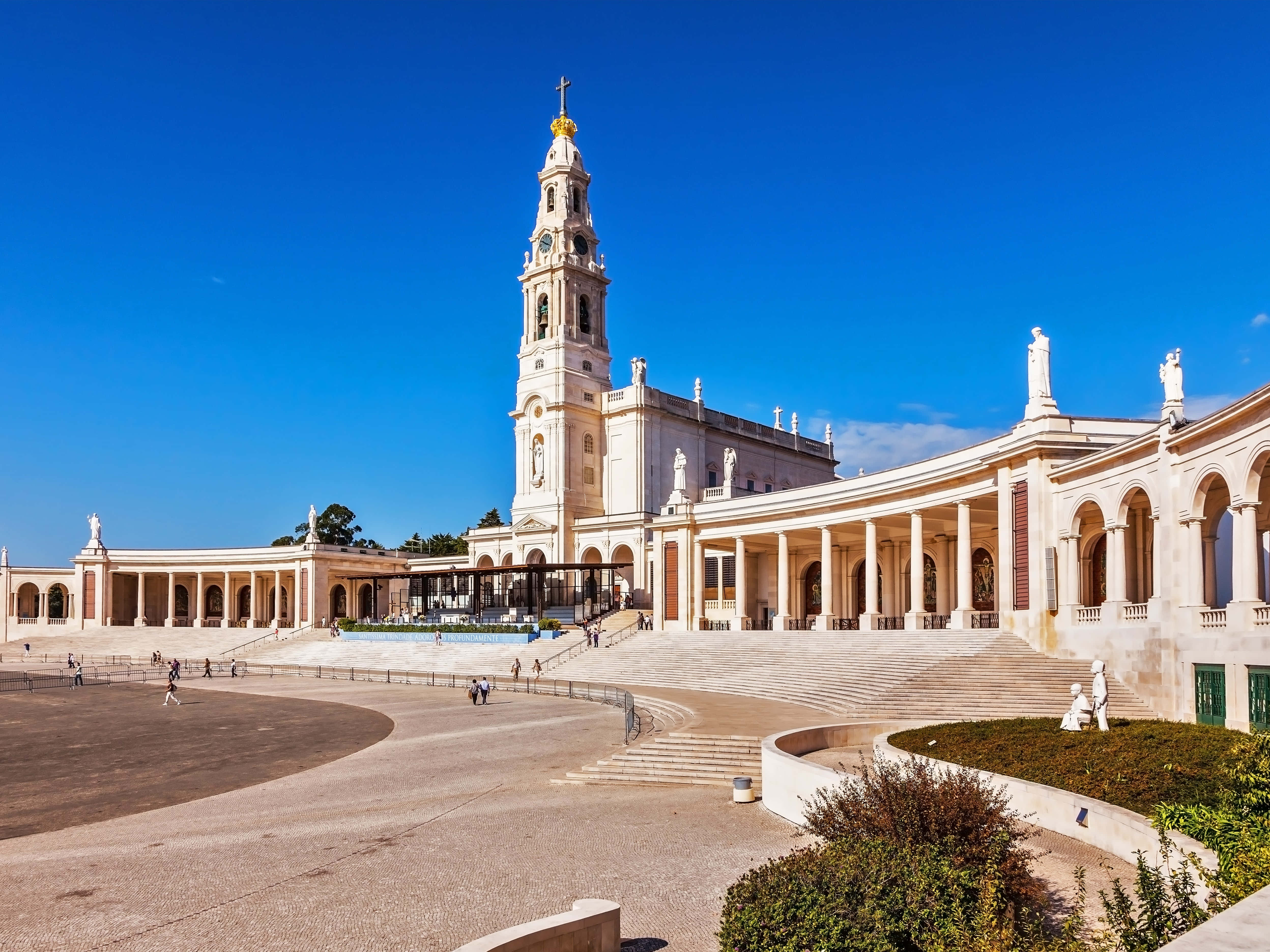 Portugal 桌布 壁紙 — 大型白色教堂，高聳鐘樓和拱形柱廊，明亮藍天中散佈著雲朵。