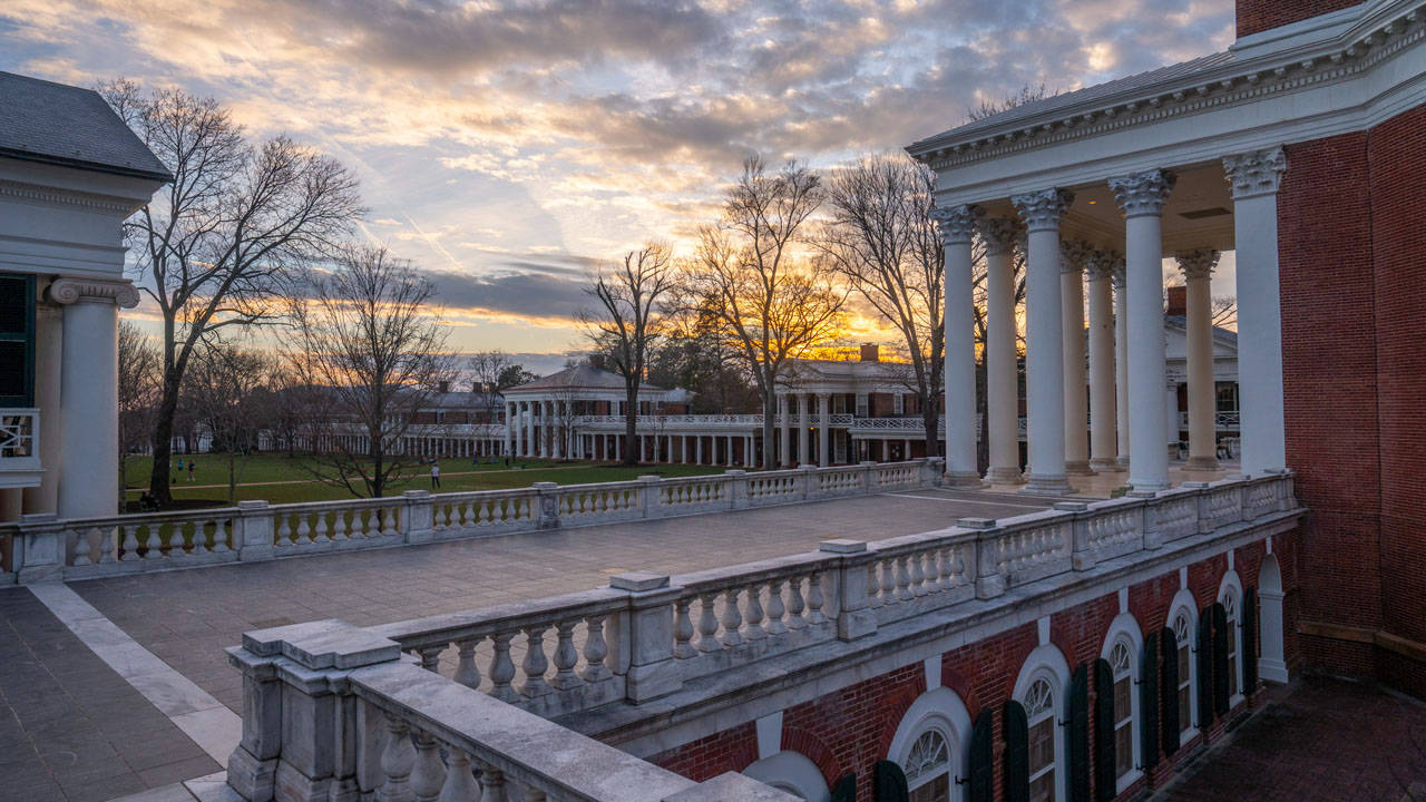 Virginia 桌布 壁紙 — 大型磚砌白色柱大學建築沐浴在金色夕陽光中，襯著光禿的樹木和多雲的天空。