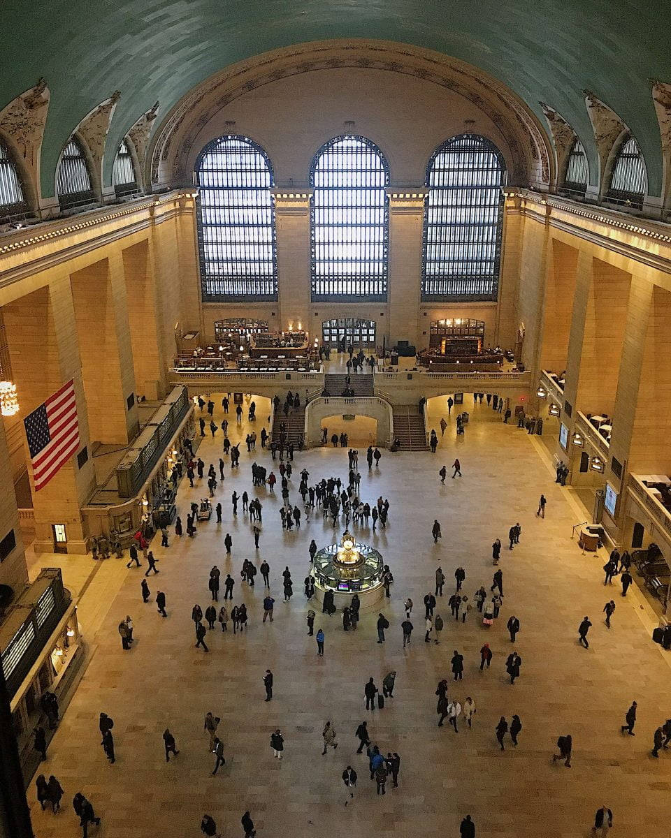 New York 桌布 壁紙 — 大型繁忙的火車站，擁有高拱形天花板、彩色玻璃窗，旅客在寬敞的大廳中穿梭。