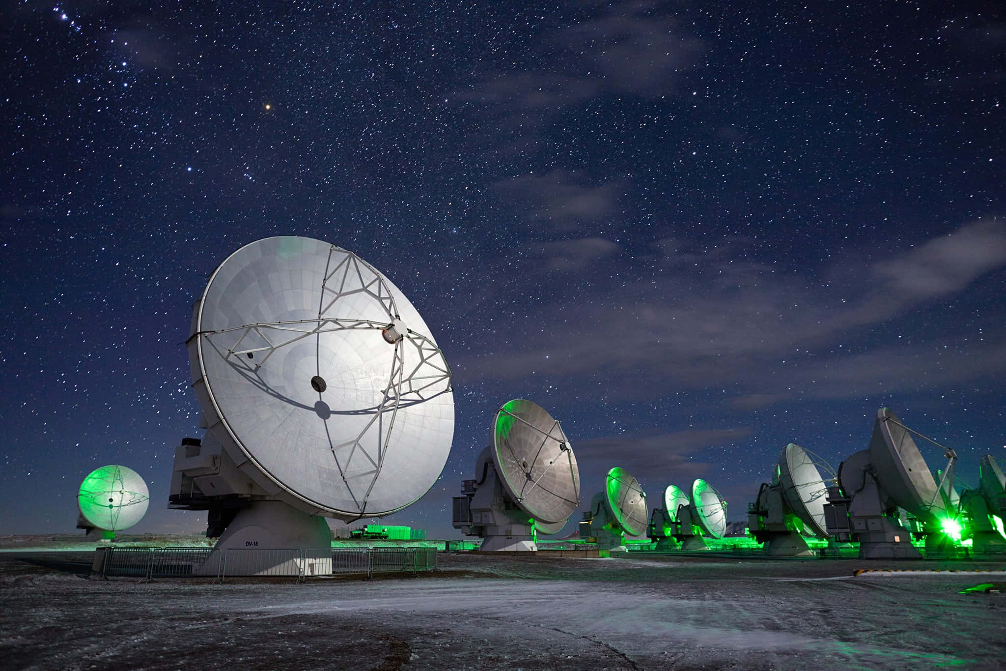 Radio Telescope 桌布 壁紙 — 大型電波望遠鏡在偏遠的沙漠景觀中，於繁星點點的夜空下發出綠色光芒。
