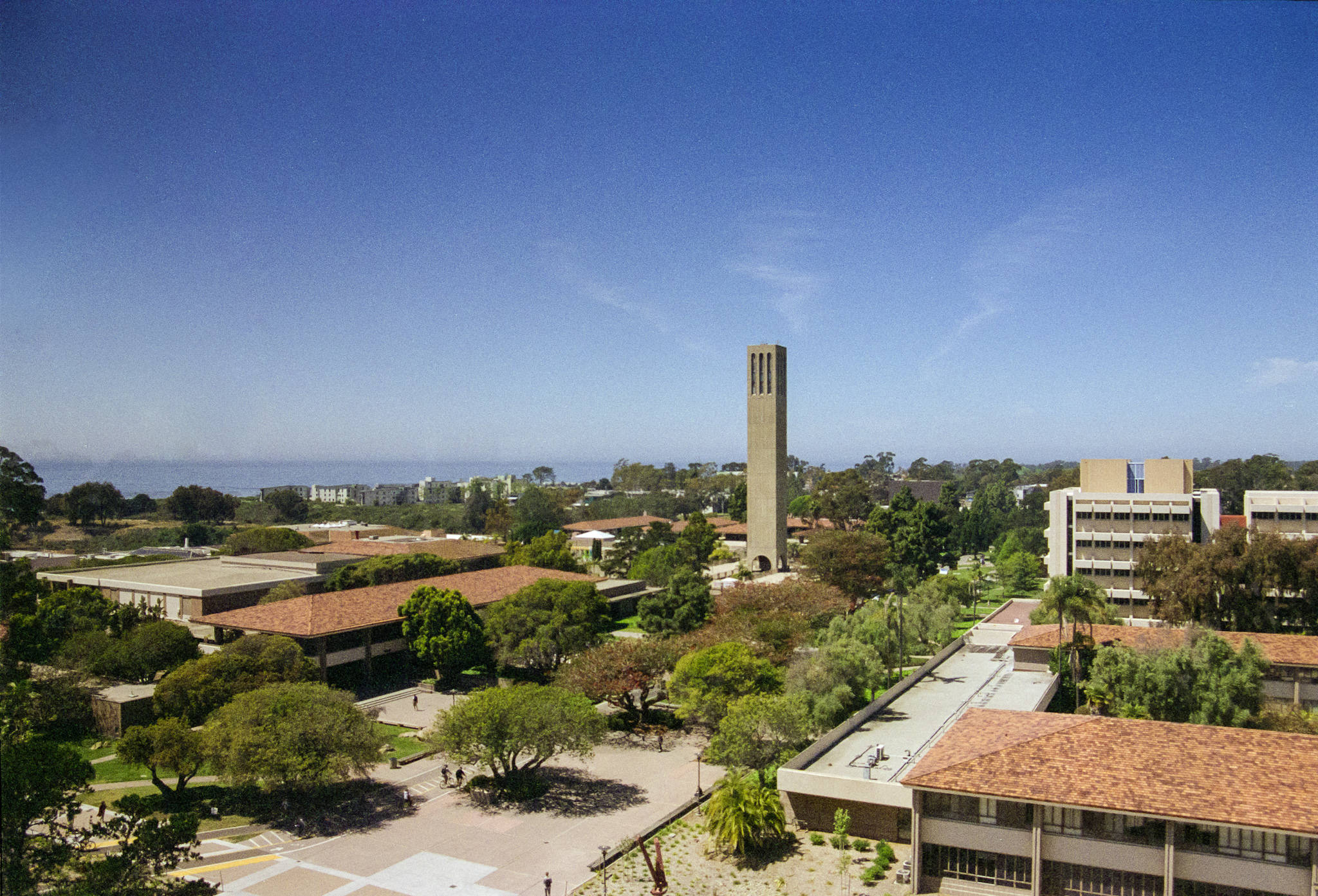 Ucsb 桌布 壁紙 — 大學校園的鳥瞰圖，有一座高大的鐘樓，周圍是紅頂建築和茂密的綠樹，在清澈的藍天下。