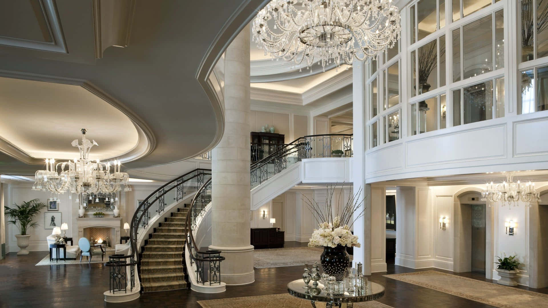 Interior Design 桌布 壁紙 — 大宅門廳，設有弧形樓梯、水晶吊燈和優雅白色圓柱，在柔和燈光下更顯氣派。