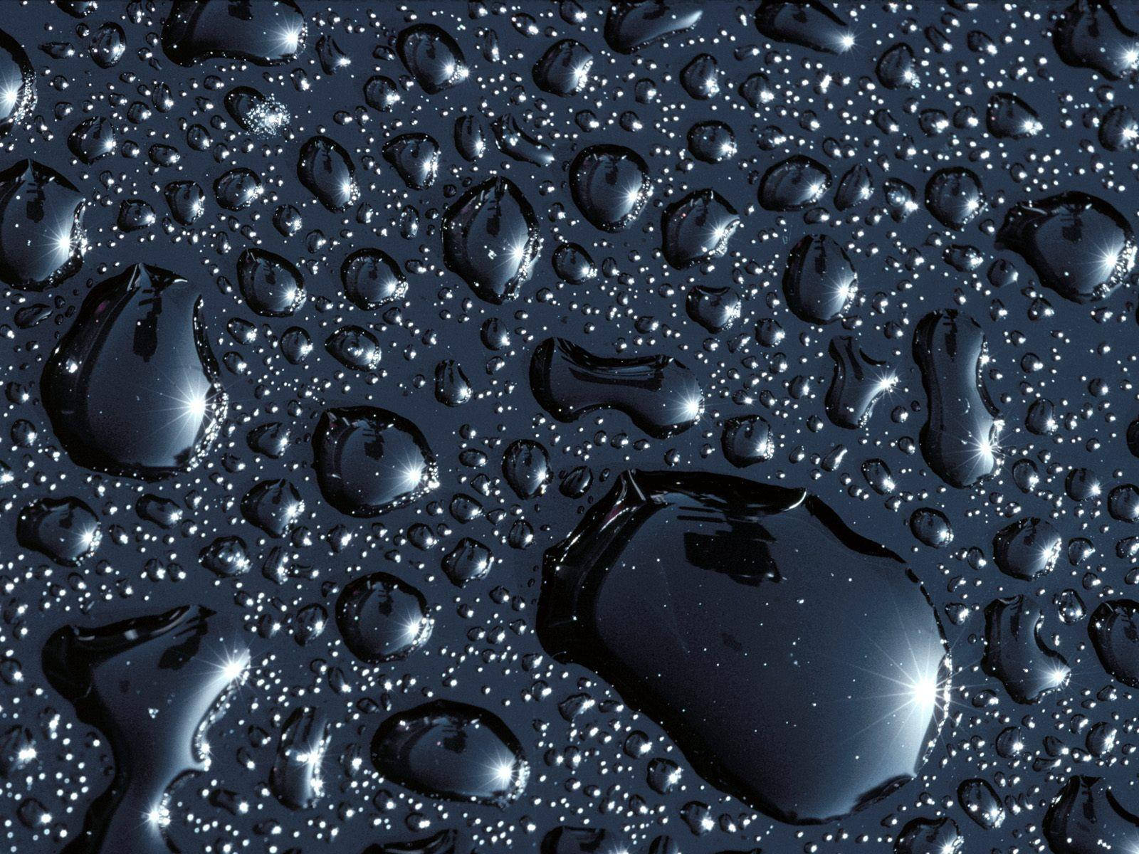 Water Drop 桌布 壁紙 — 大小不一、閃閃發光的水滴停留在深色表面上，反射出明亮的星狀高光。