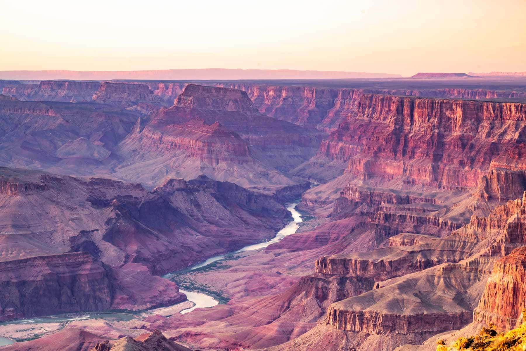 grand canyon 桌布 壁紙 — 大峽谷上令人驚嘆的日出，層層疊疊的紅色岩層和蜿蜒的河流在下方。