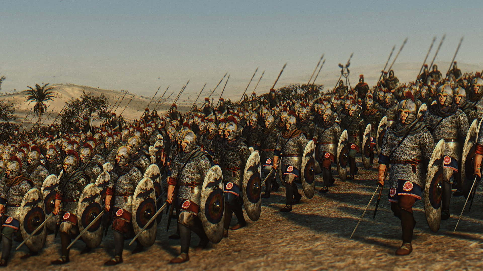 電玩遊戲 桌布 壁紙 — 大批全副武裝的羅馬軍團士兵在朦朧的天空下，以緊密陣型穿越烈日曝曬的沙漠平原。