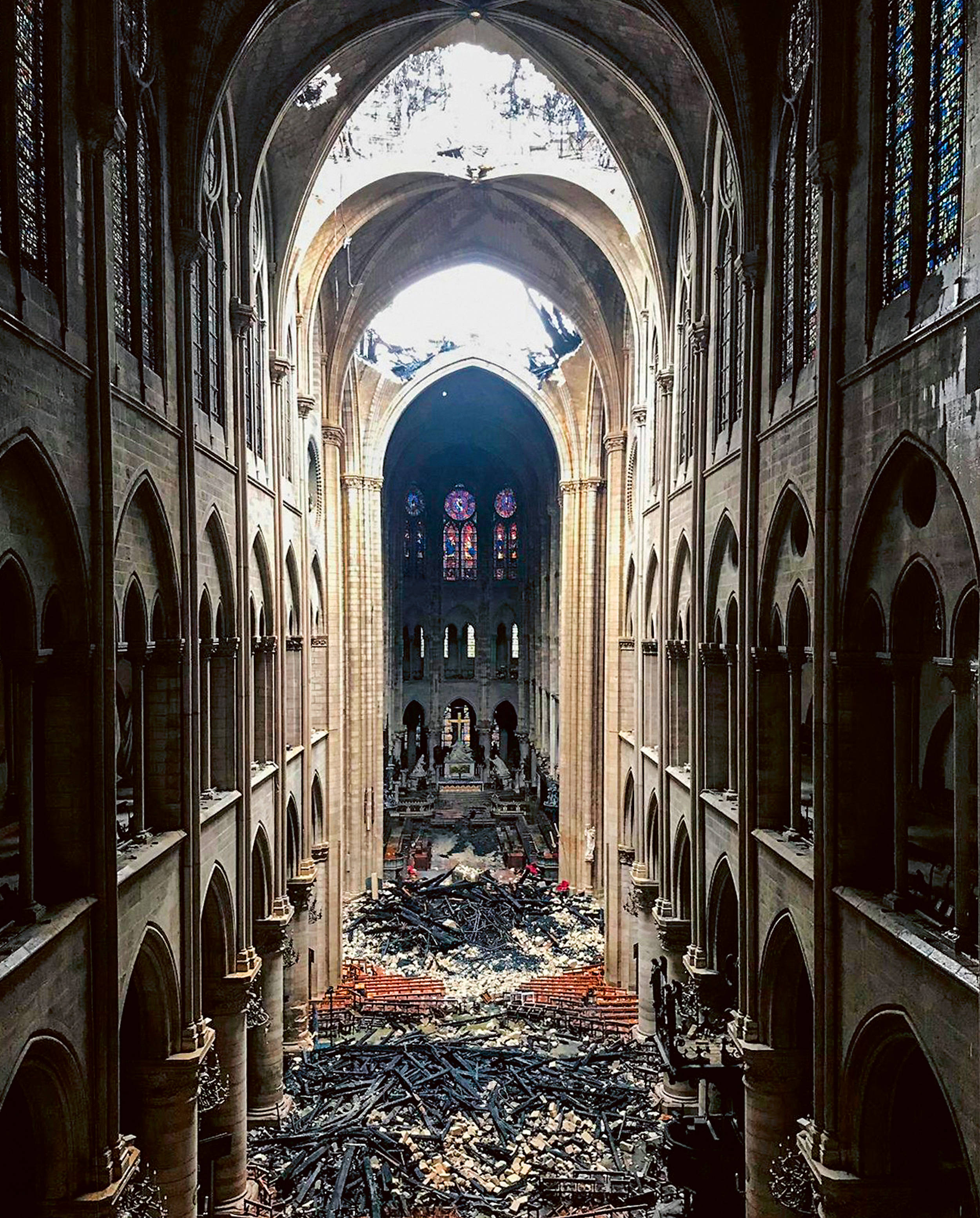 Notre Dame 桌布 壁紙 — 大教堂的中殿已成廢墟，地上散落著碎片，上方是破碎的彩繪玻璃窗。