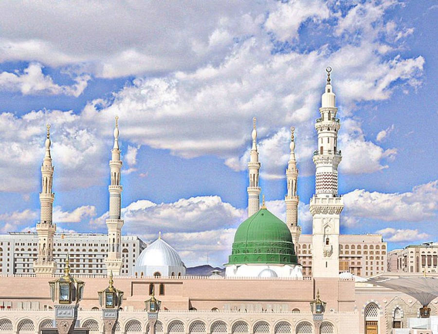 Madina 桌布 壁紙 — 大清真寺，擁有綠色和銀色圓頂及高聳宣禮塔，在明亮的藍天下有蓬鬆的白雲。