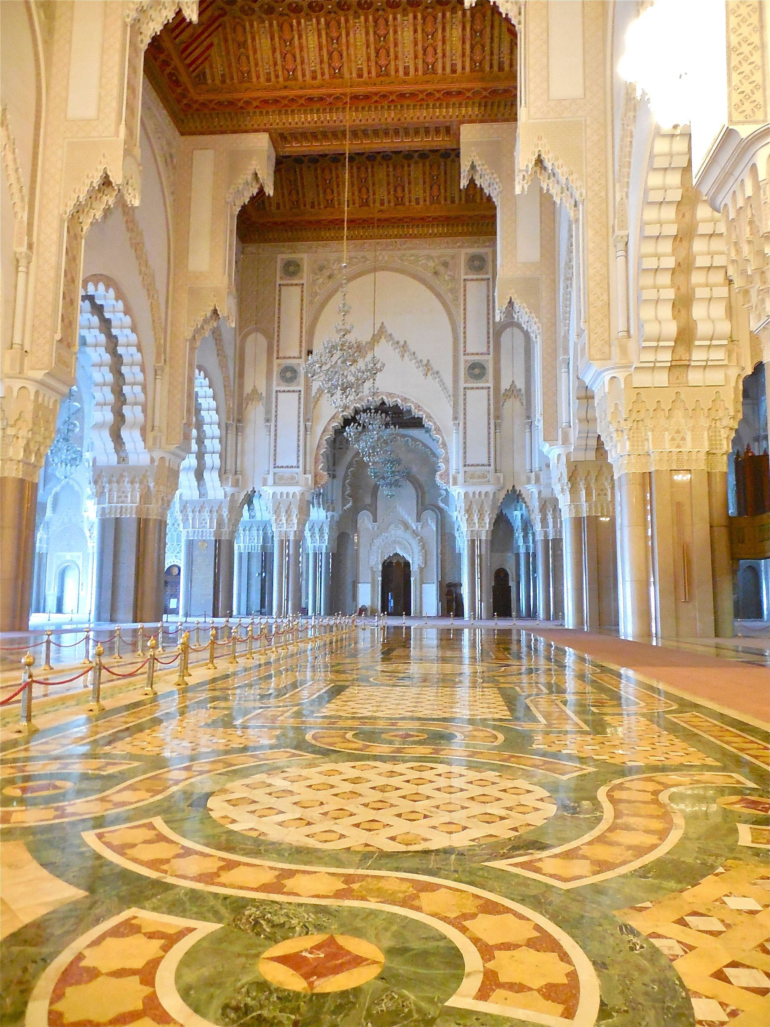 Morocco 桌布 壁紙 — 大清真寺內部，裝飾華麗的拱門、大理石地板和金色天花板細節，沐浴在柔和自然光中。