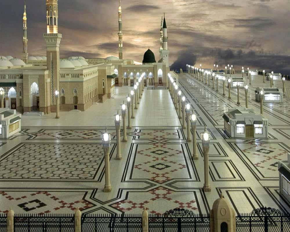 Medina 桌布 壁紙 — 大清真寺庭院在黃昏時分被照亮，對稱的小徑和宣禮塔在多雲的天空下。