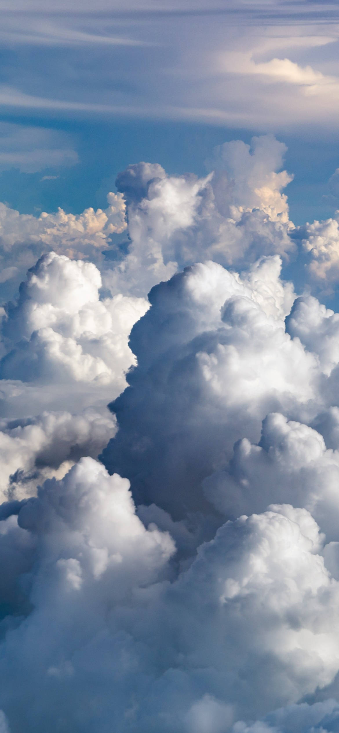 桌布 壁紙 — 大片蓬鬆的白雲在清澈的藍天下飄動，柔和的金色陽光照亮它們紋理分明的頂部。