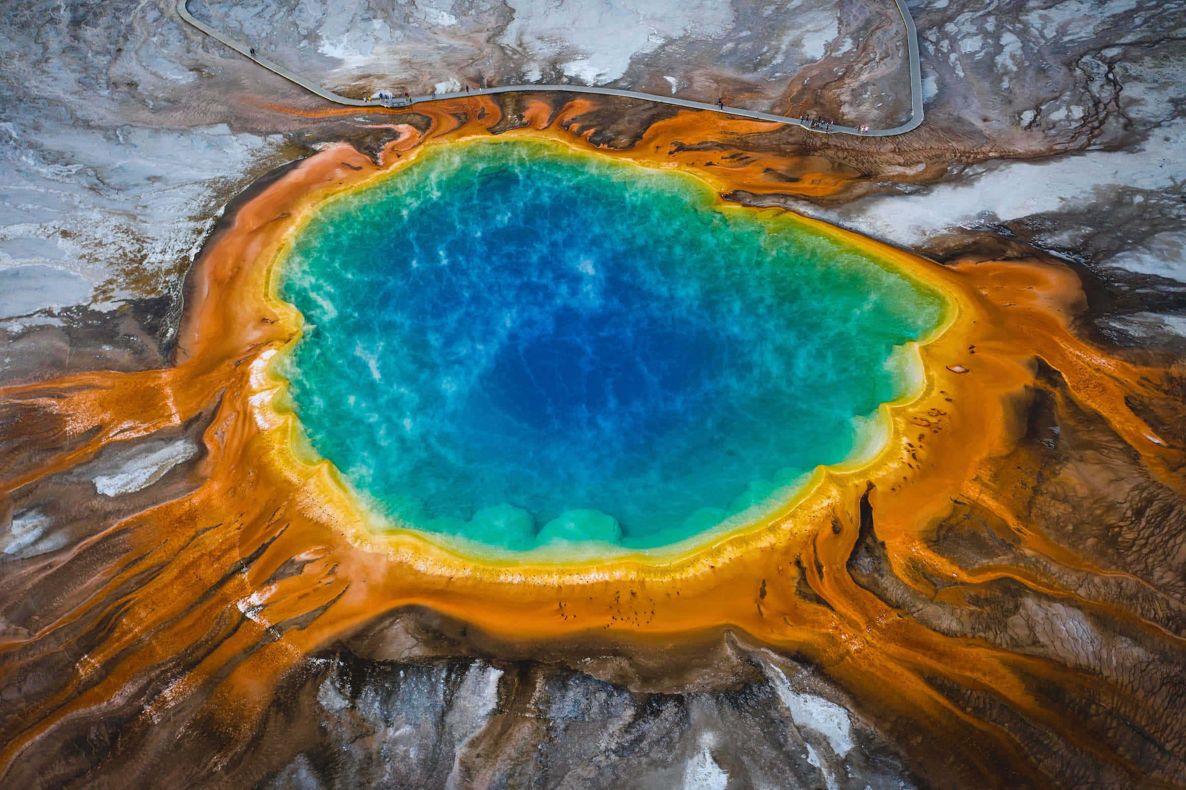 Yellowstone Geysers 桌布 壁紙 — 大稜鏡溫泉的鳥瞰圖，展示鮮豔的藍綠色水域，周圍環繞著橙色和黃色的礦物環。
