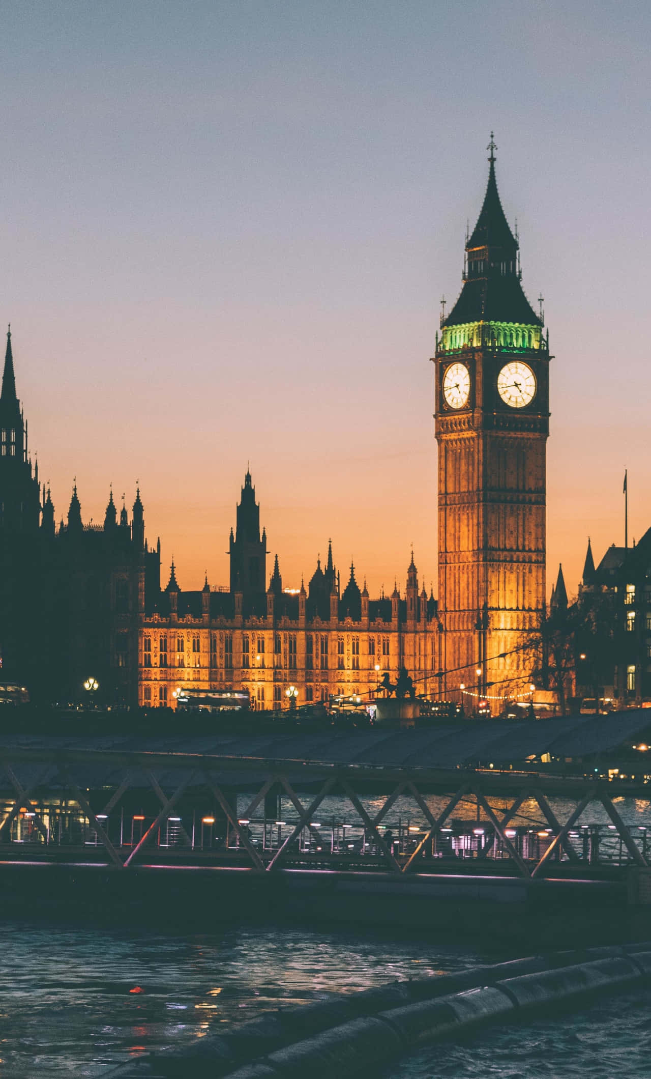 London iPhone 桌布 壁紙 — 大笨鐘和國會大廈在黃昏時溫暖地發光，倒影在下面的泰晤士河上閃爍。
