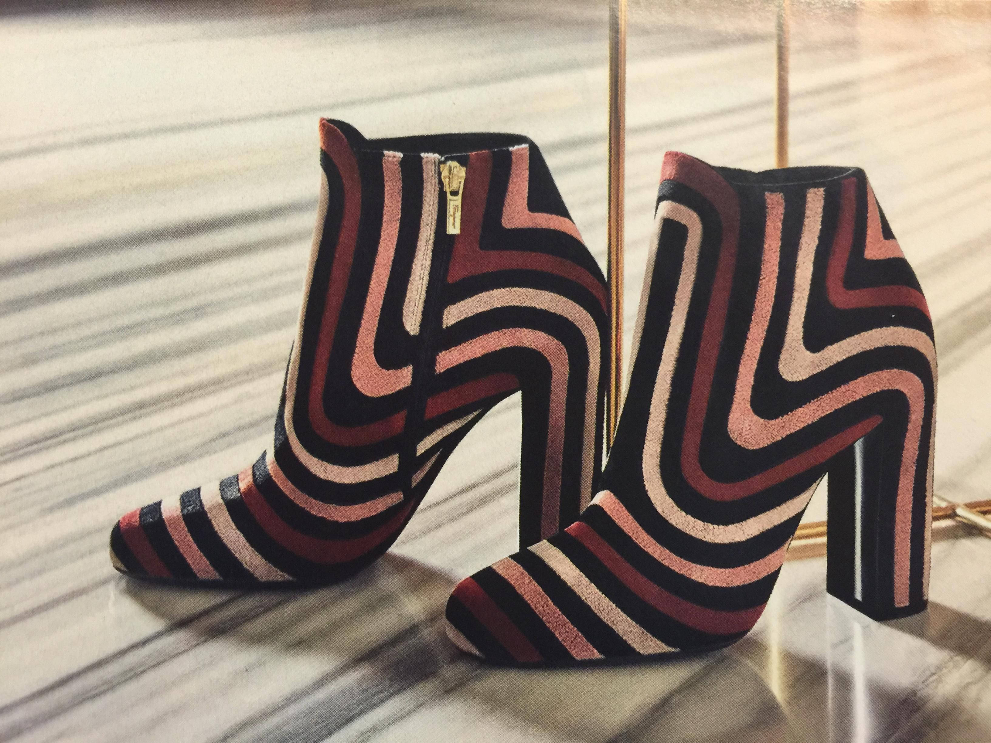 Ferragamo 桌布 壁紙 — 大膽圖案的及踝靴，帶有玫瑰色、黑色和米色的鋸齒條紋，放置在反光的大理石地板上。