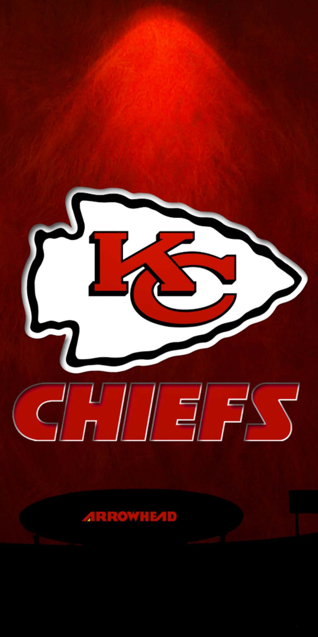 Kansas City Chiefs Logo 桌布 壁紙 — 大膽的堪薩斯城酋長隊標誌在聚光燈下發光，背景為有紋理的紅色，下方可見「Arrowhead」。