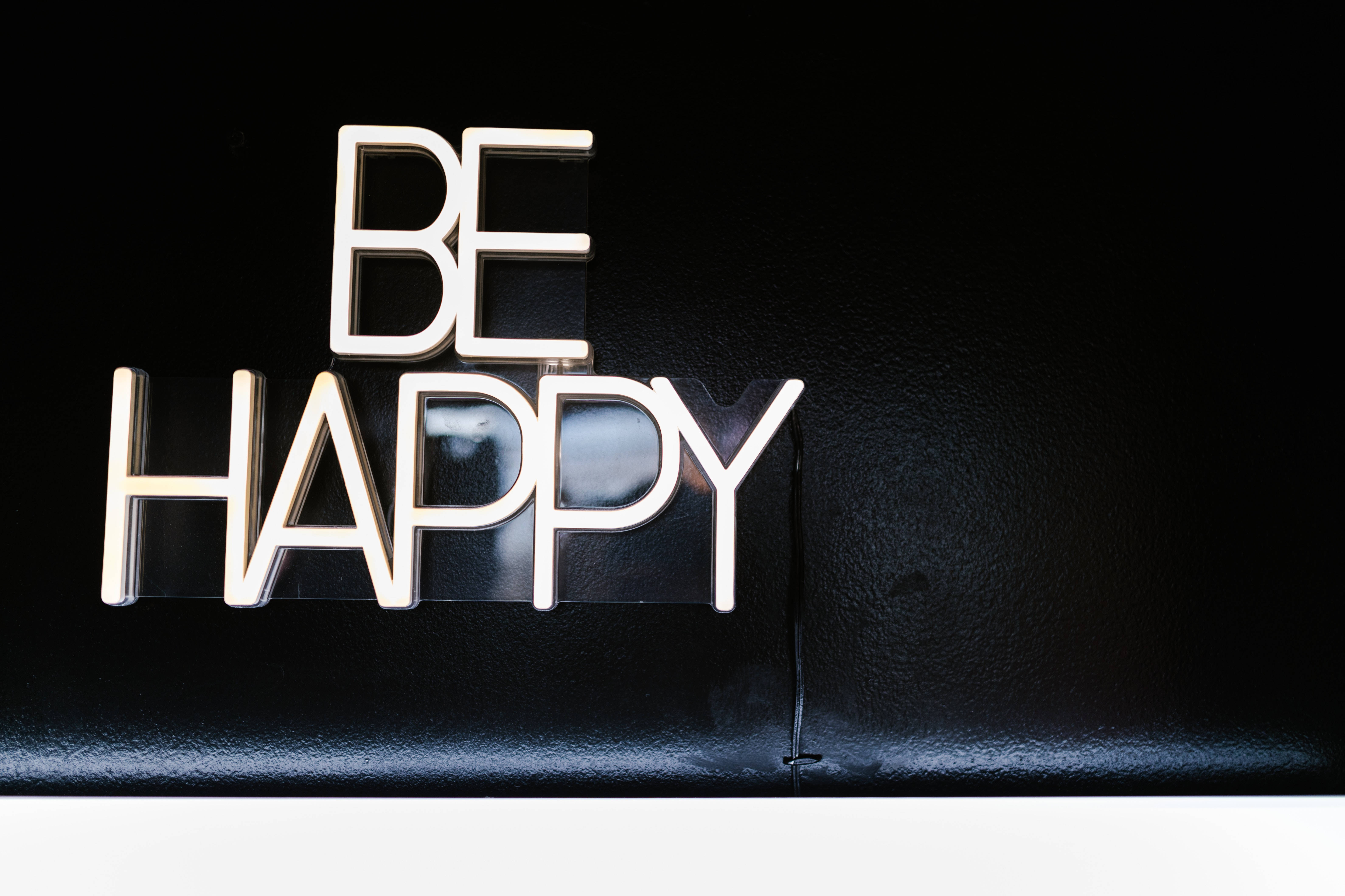 快樂 桌布 壁紙 — 大膽的白色3D字母拼出「BE HAPPY」，在帶有柔和光線的紋理黑色背景上脫穎而出。