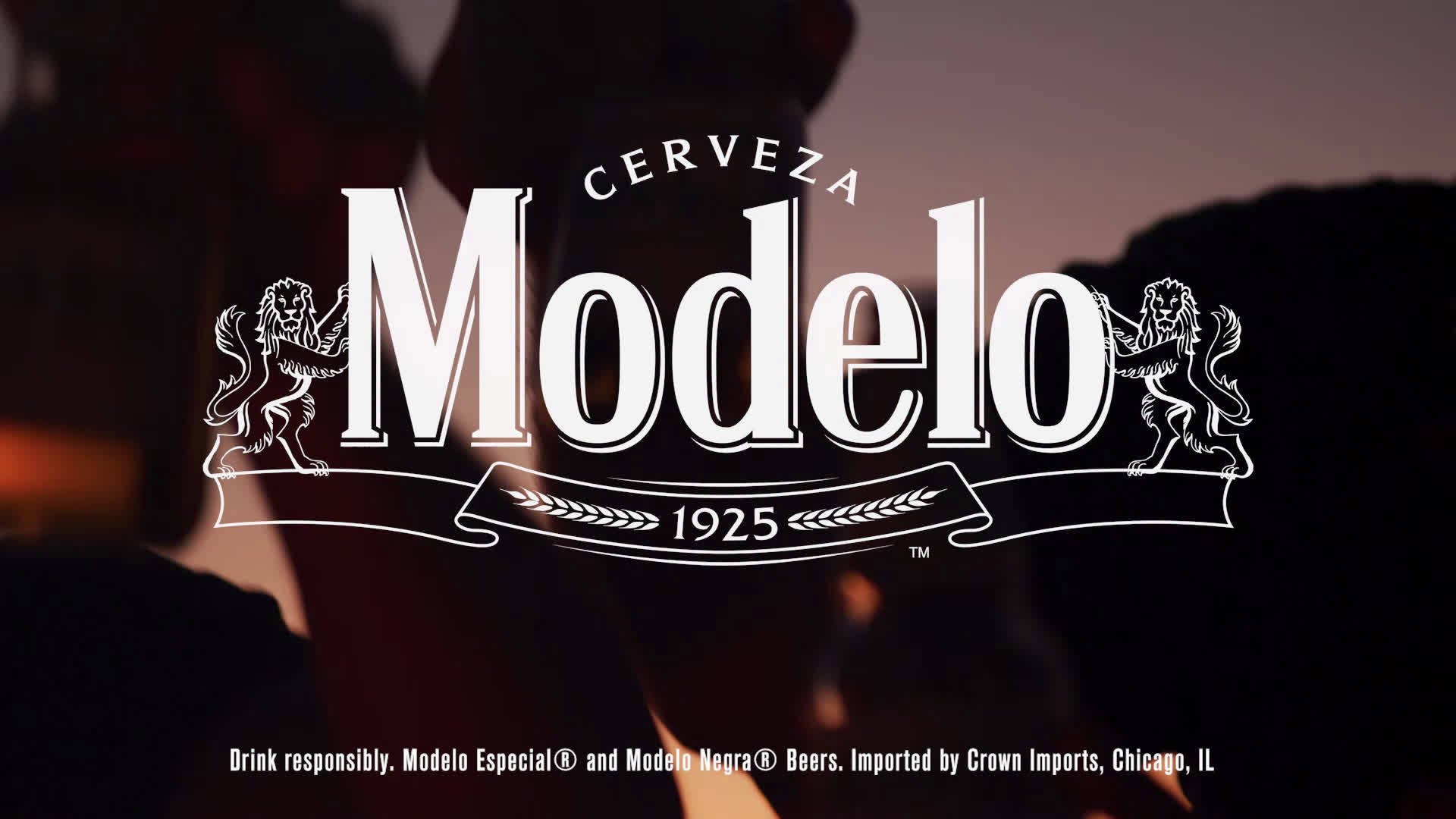 Beer 桌布 壁紙 — 大膽的白色Modelo標誌，帶有獅子徽章和1925年橫幅，在溫暖的環境照明下，在黑暗模糊的背景中脫穎而出。