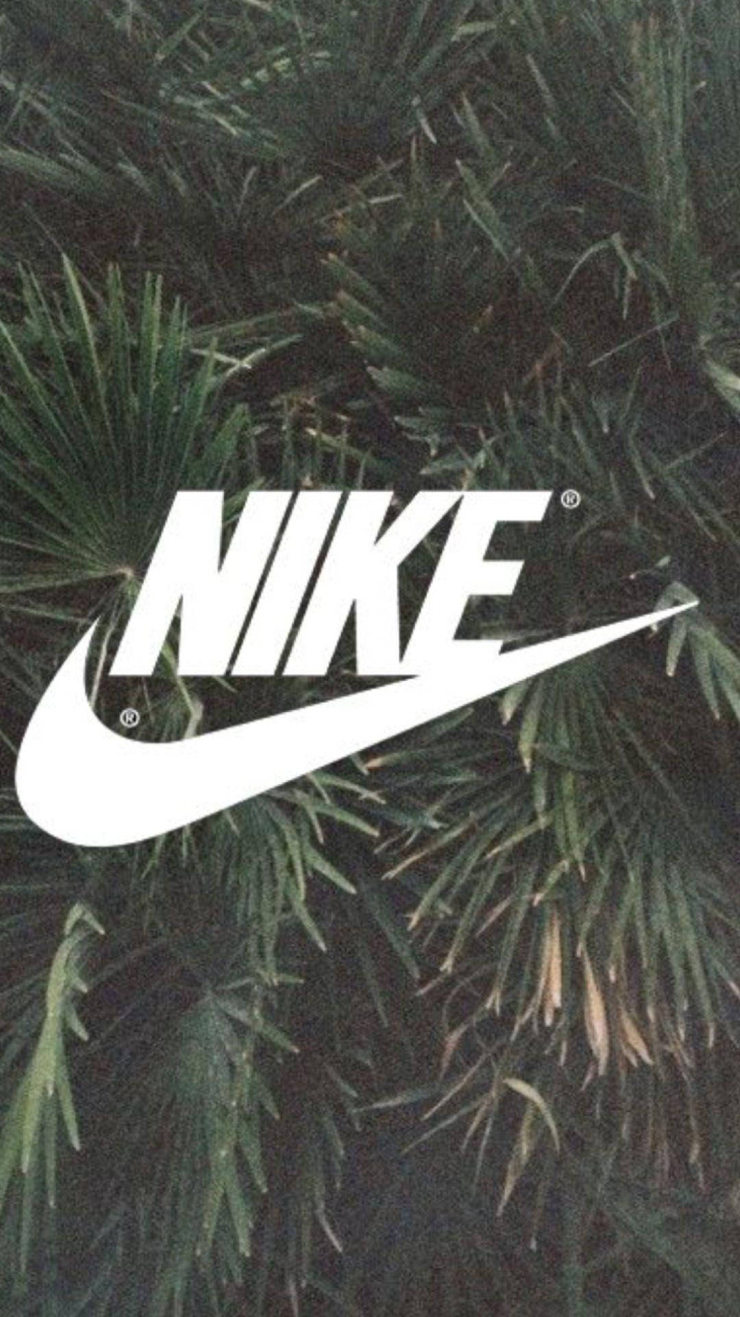 Nike iPhone 桌布 壁紙 — 大膽的白色Nike標誌覆蓋在密集的深綠色棕櫚葉上，形成粗糙紋理的壁紙。