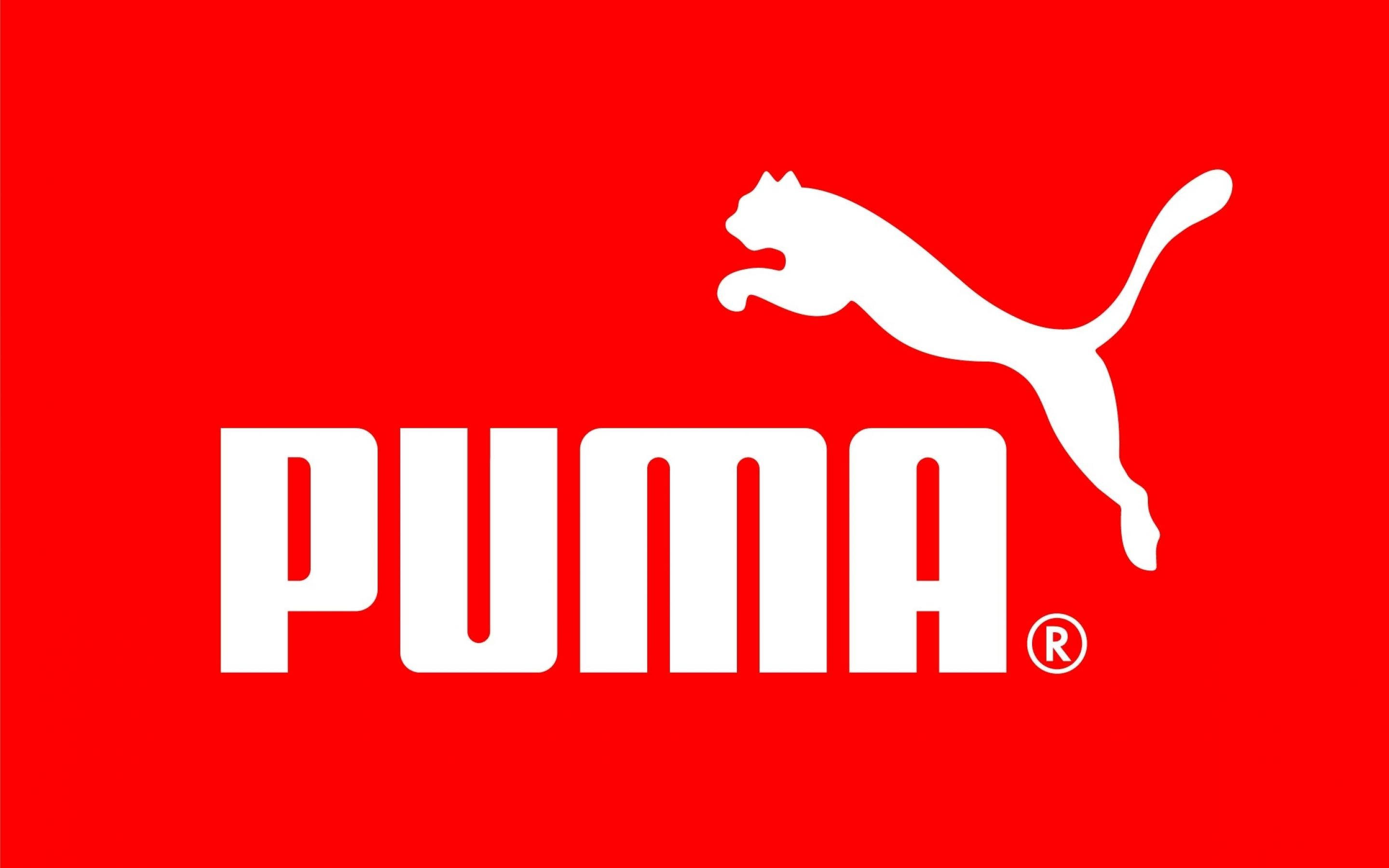 Puma 桌布 壁紙 — 大膽的白色Puma標誌，帶有跳躍的貓剪影，襯托鮮豔的紅色背景。