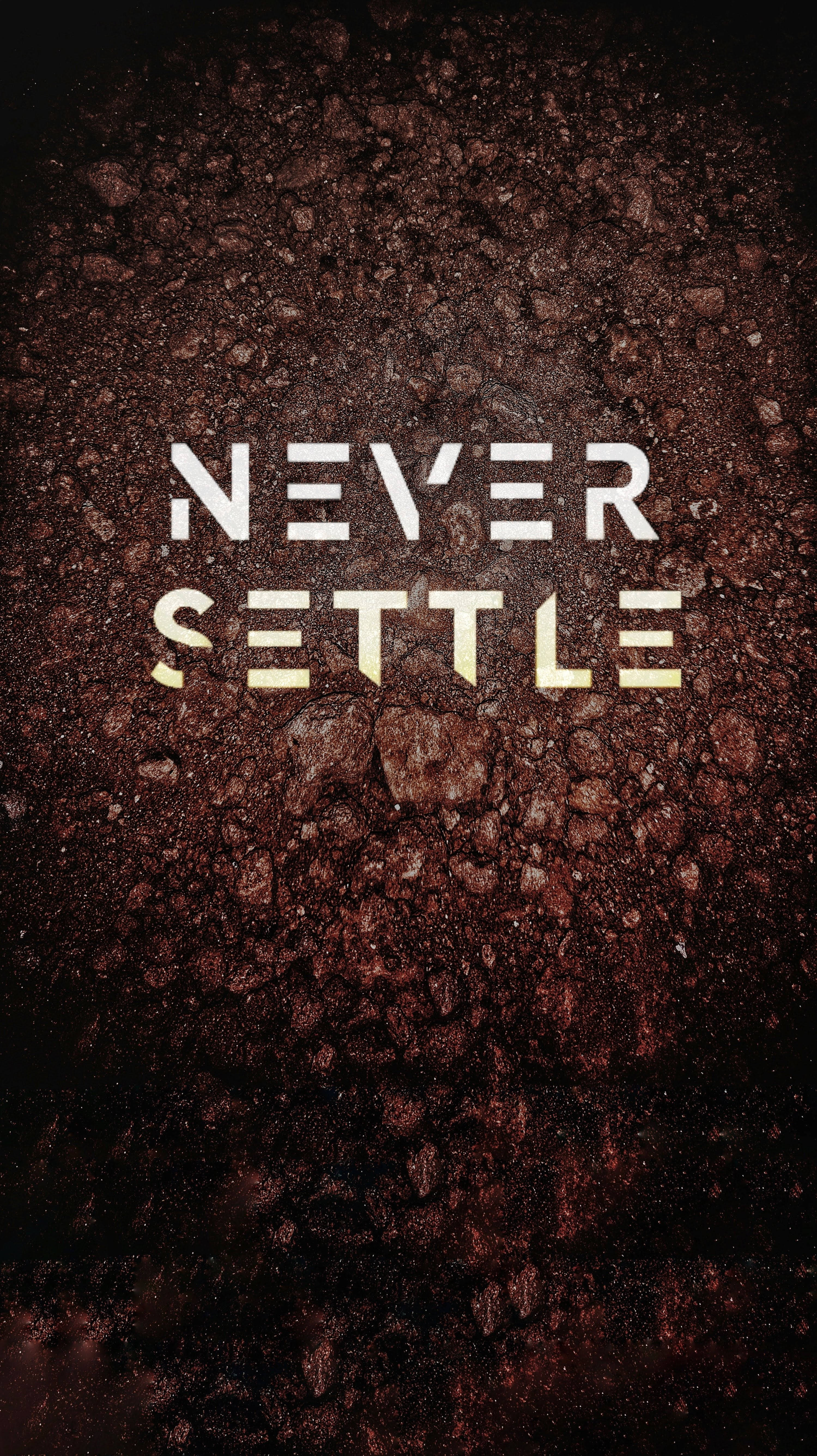  壁紙 — 大膽的白色和金色文字「NEVER SETTLE」從深色紋理土壤中浮現，背景為黑色。