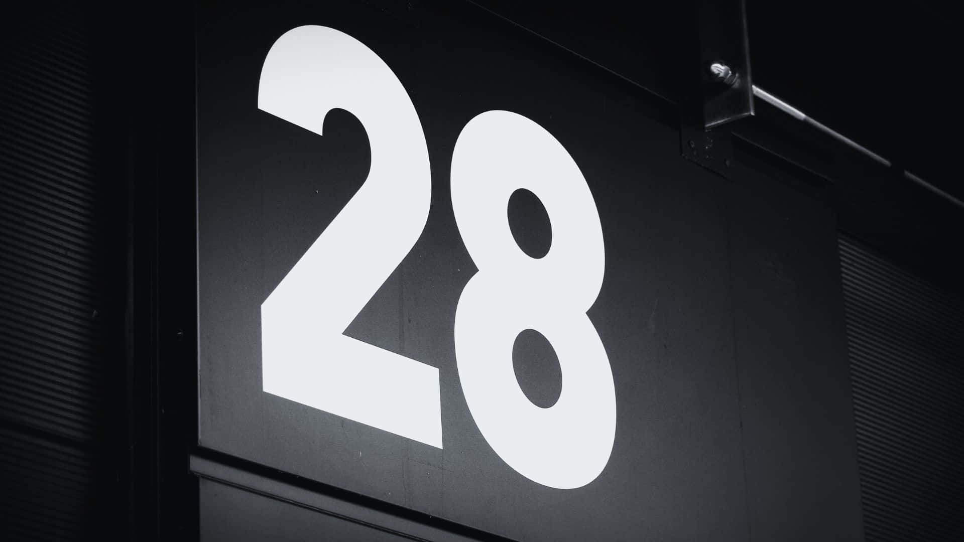 Black And White Number 桌布 壁紙 — 大膽的白色數字28在極簡城市環境的深色紋理牆上發光。